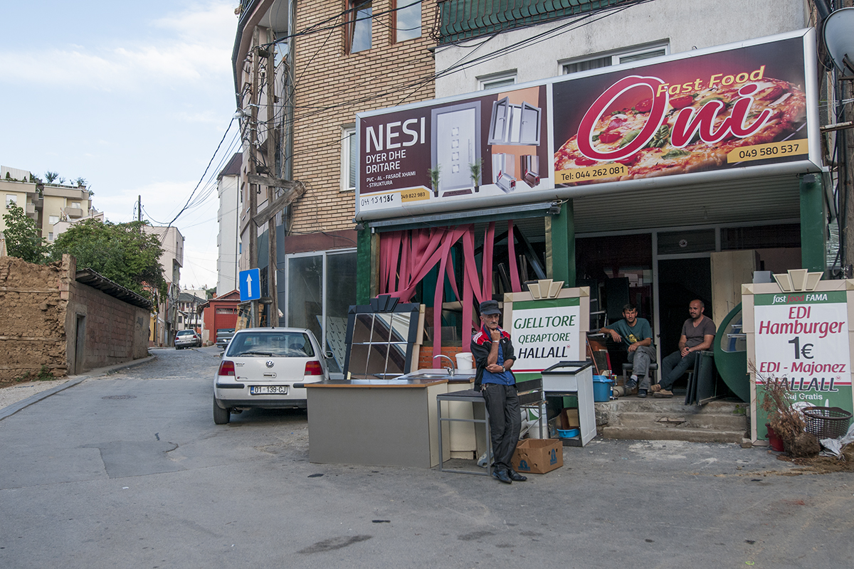 Men standing in front of a fast food restaurant where hamburger are sold for 1€ on Svetozar Markoviq street.