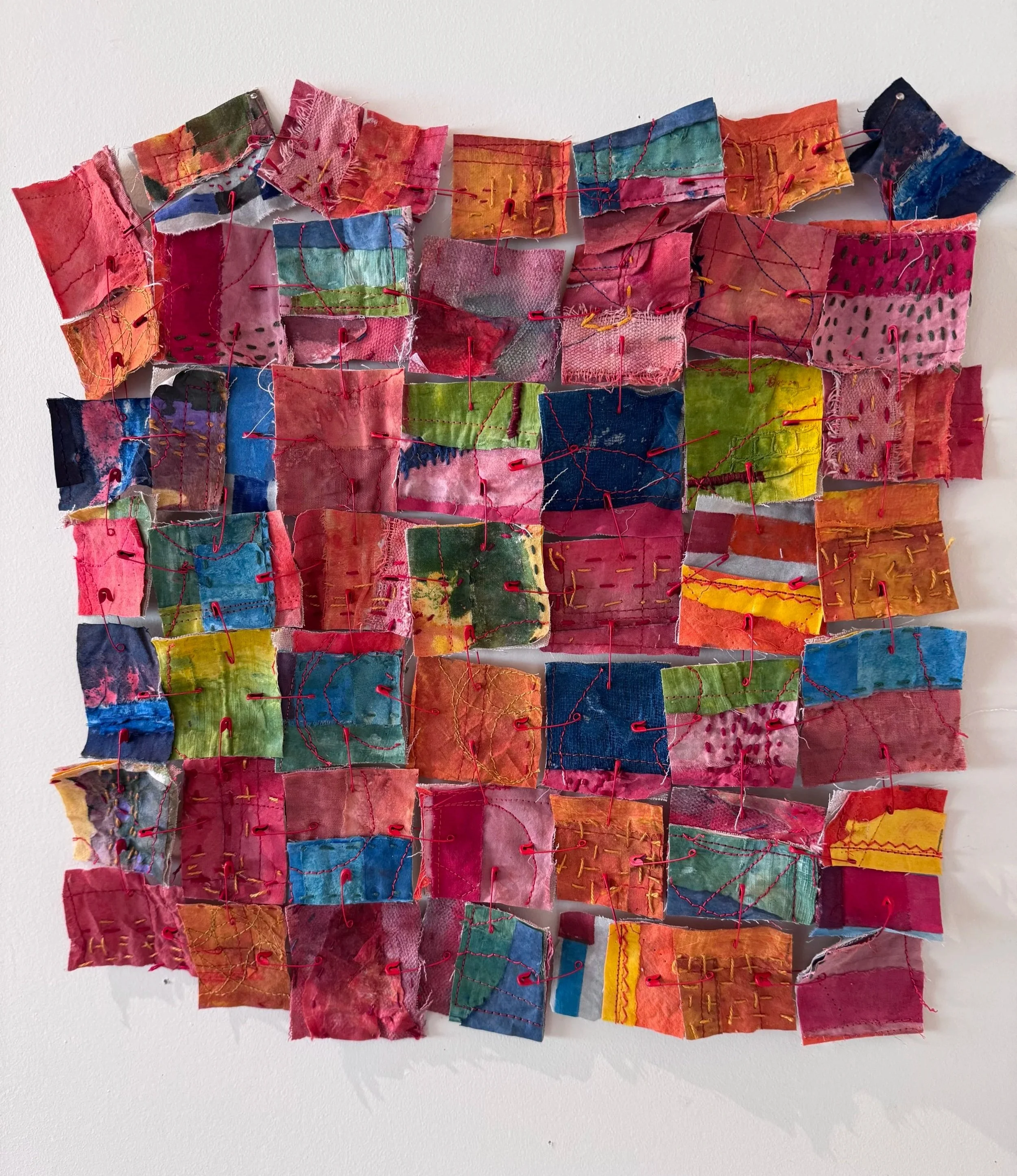 Sculpture made of multi-colored fabric squares held together with red thread
