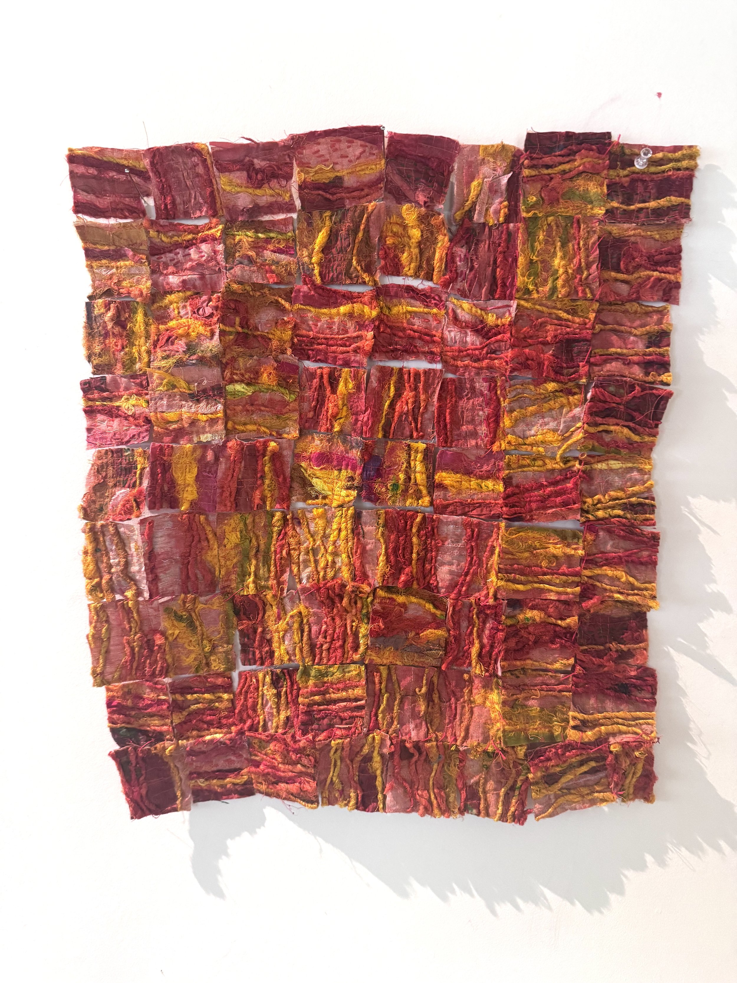 Sculpture of fabric squares in red, pink, orange, and yellow