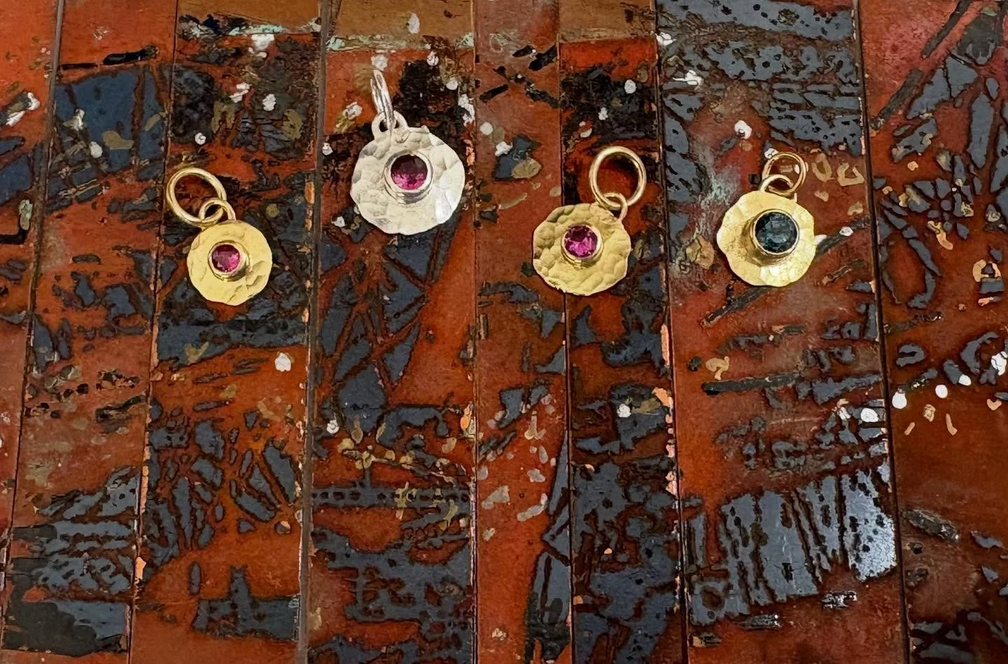 Smush pendants, glimmers of color and light; hammered gold and silver parts with sapphire and ruby settings.