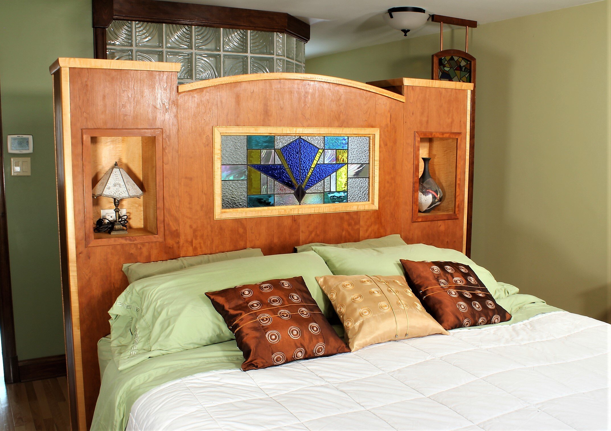 Bed side with nooks and stain glass window.