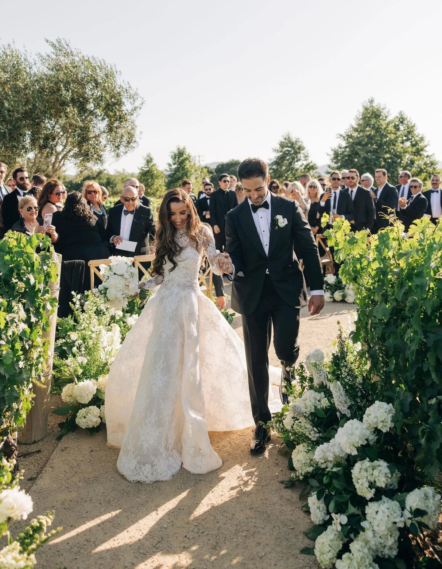 Erin &amp; Nick's ceremony in the center of @braveandmaiden's vineyard was the ideal start to their intimate black-tie wedding celebration. We still can't get over the meandering floral garden entrance @camelliafloraldesign created through the vineya