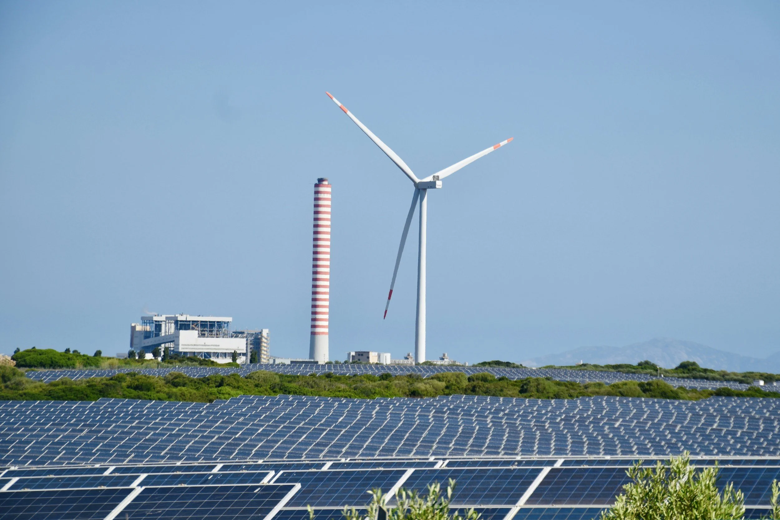 wind turbine and solar panels against a blue sky