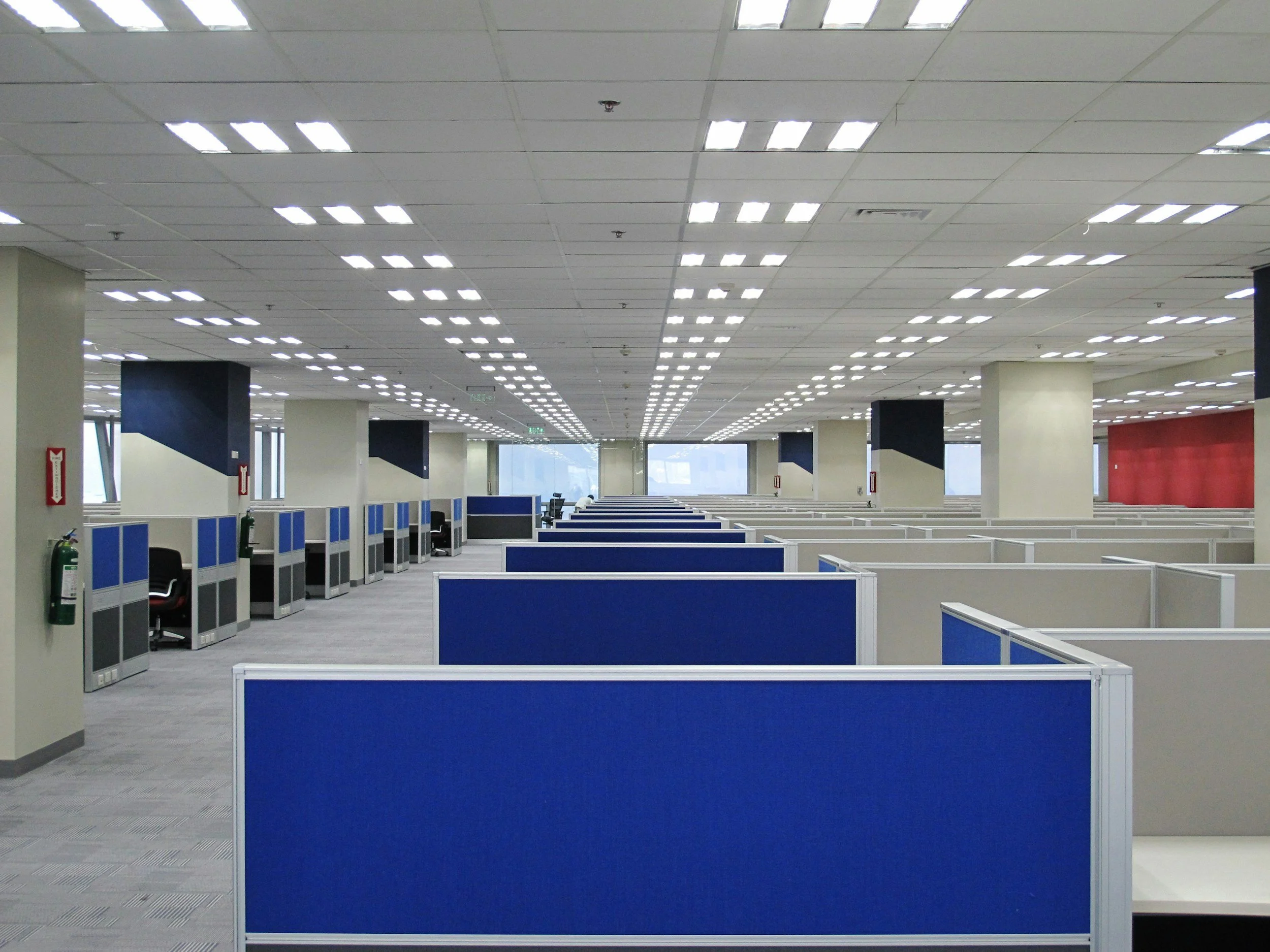 an empty office with blue and white cubicles and bright overhead lighting