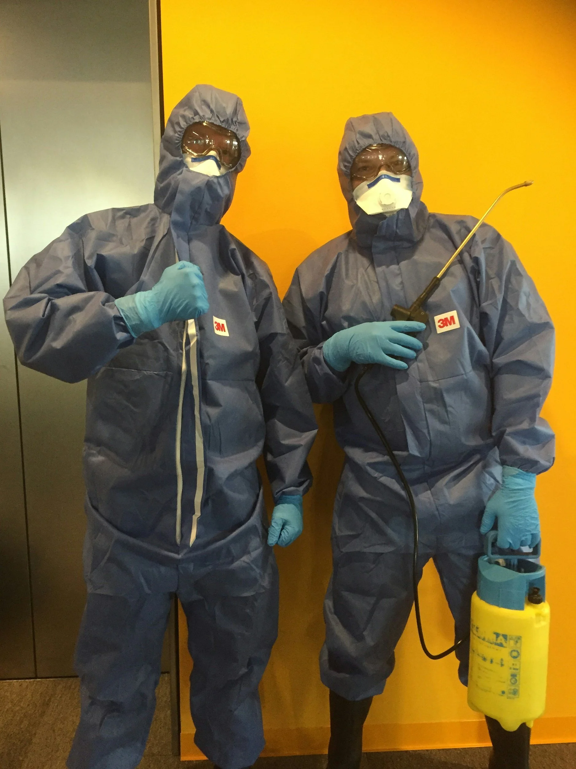 2 men on a mold remediation team in black suits and masks
