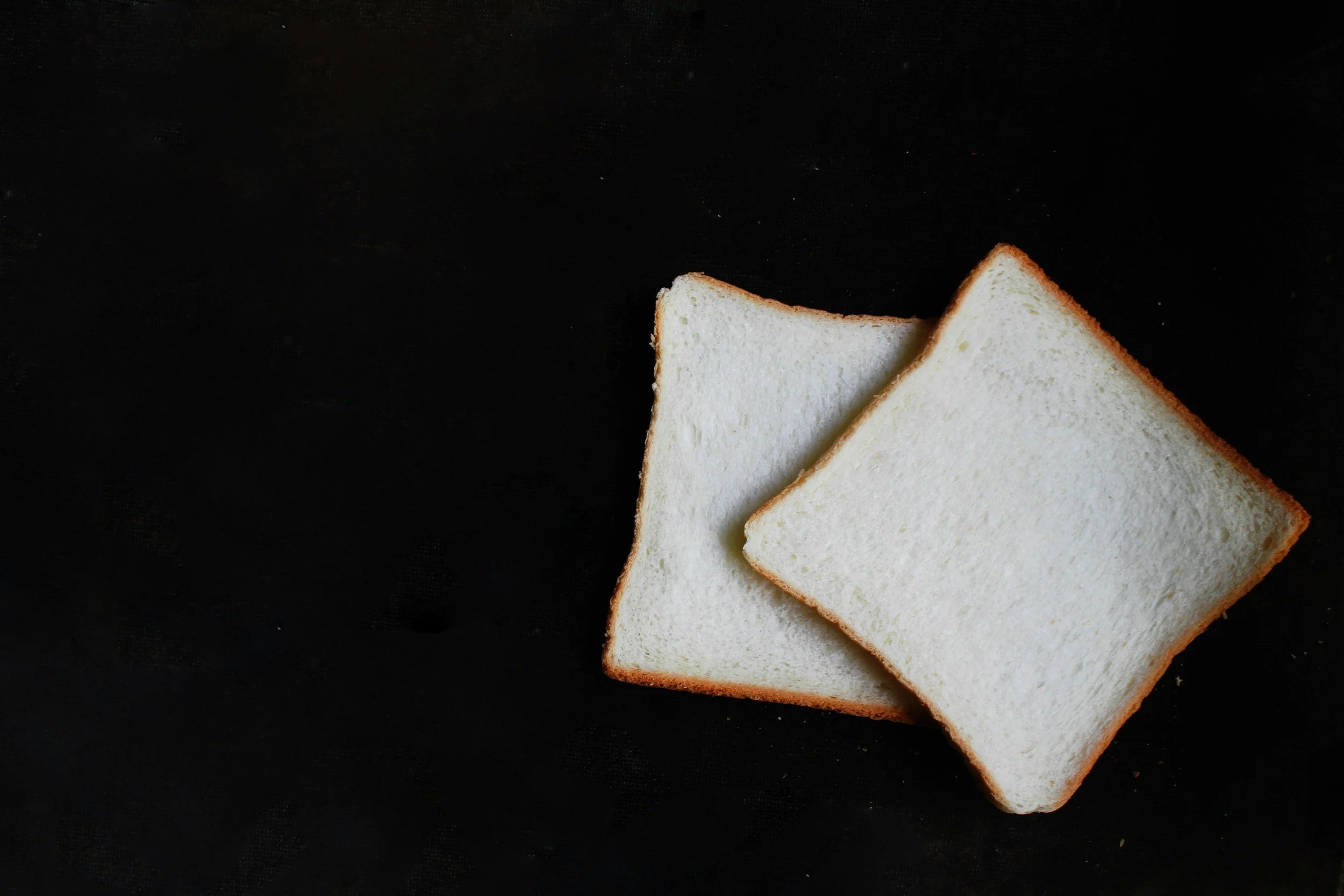 two slices of white bread against a black background