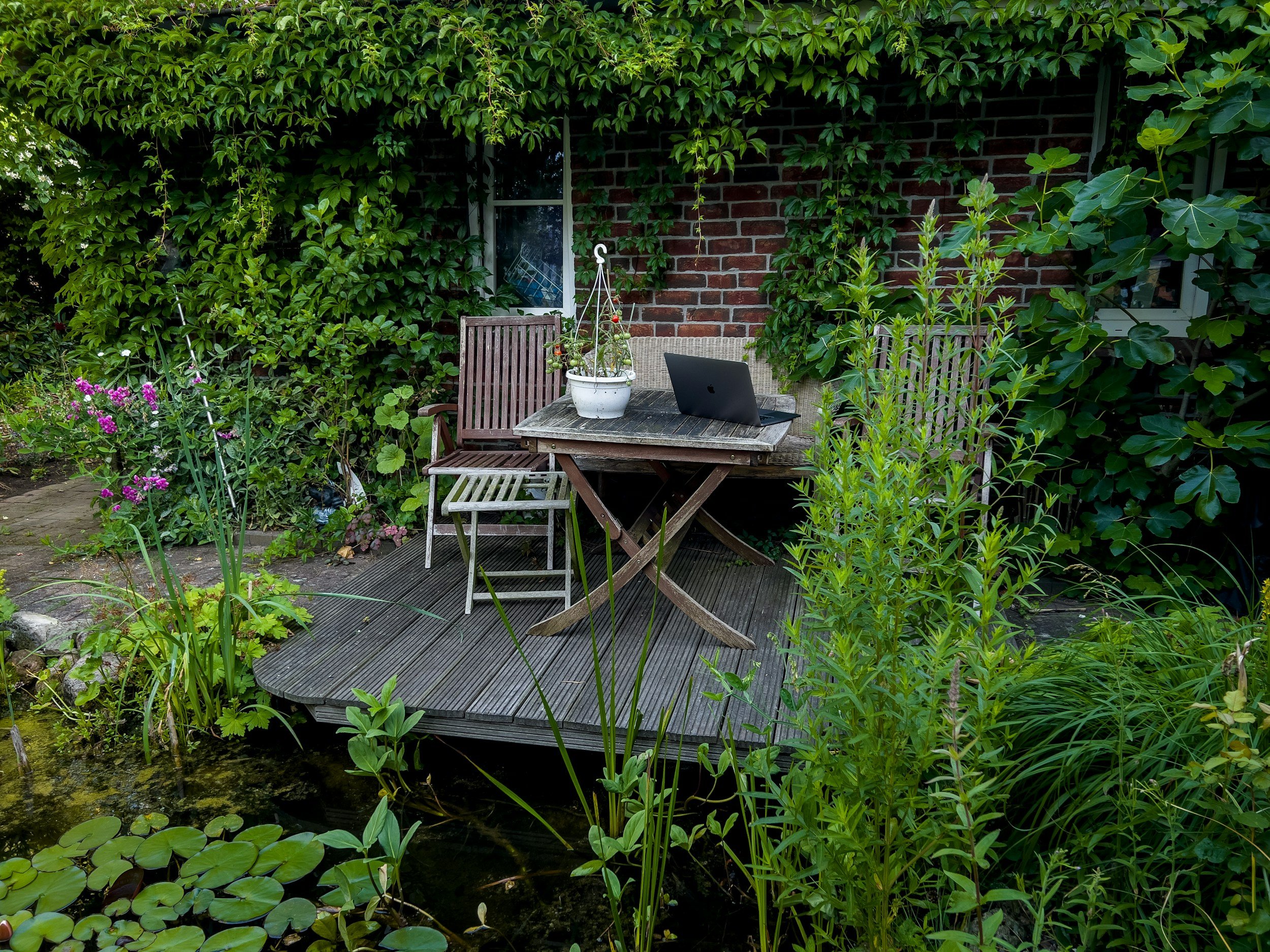 outdoor table on deck with a laptop on it in front of a small pond