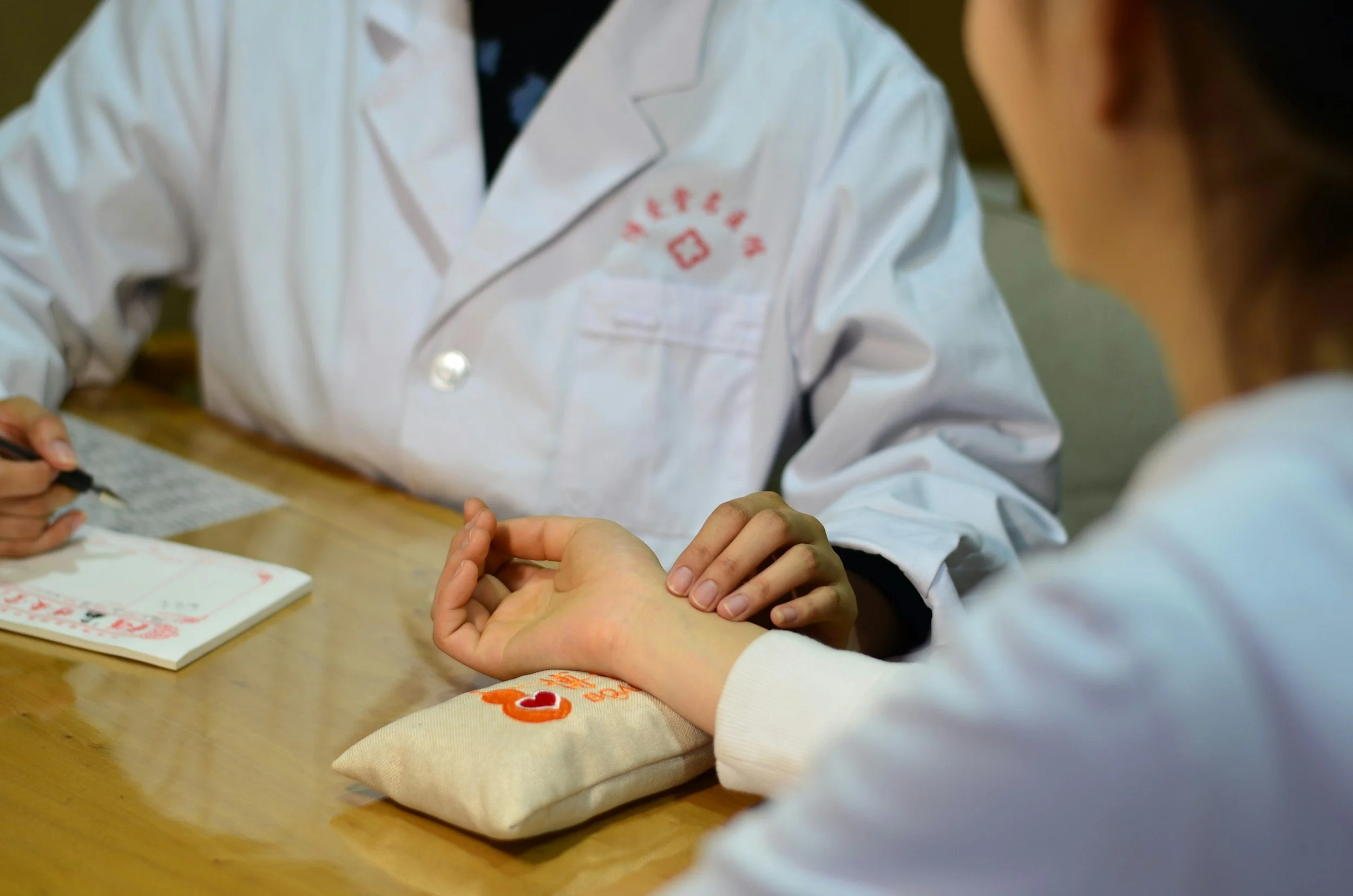 physician in white coat measuring the pulse of a patient
