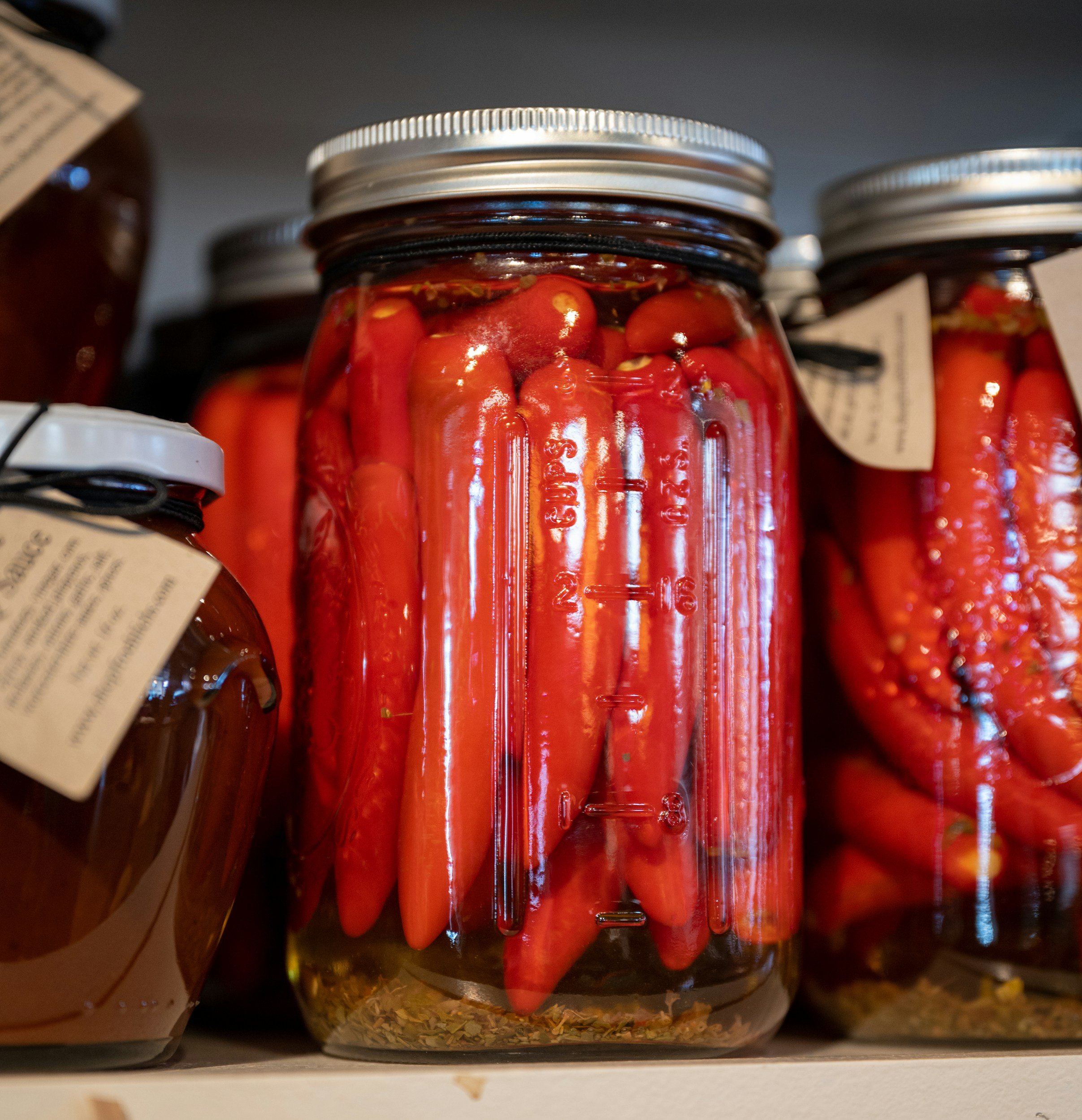 several jars of pickled hot peppers on a shelf