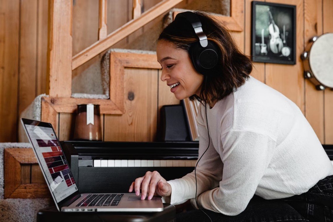 一位女士戴着耳机在笔记本电脑上听音乐