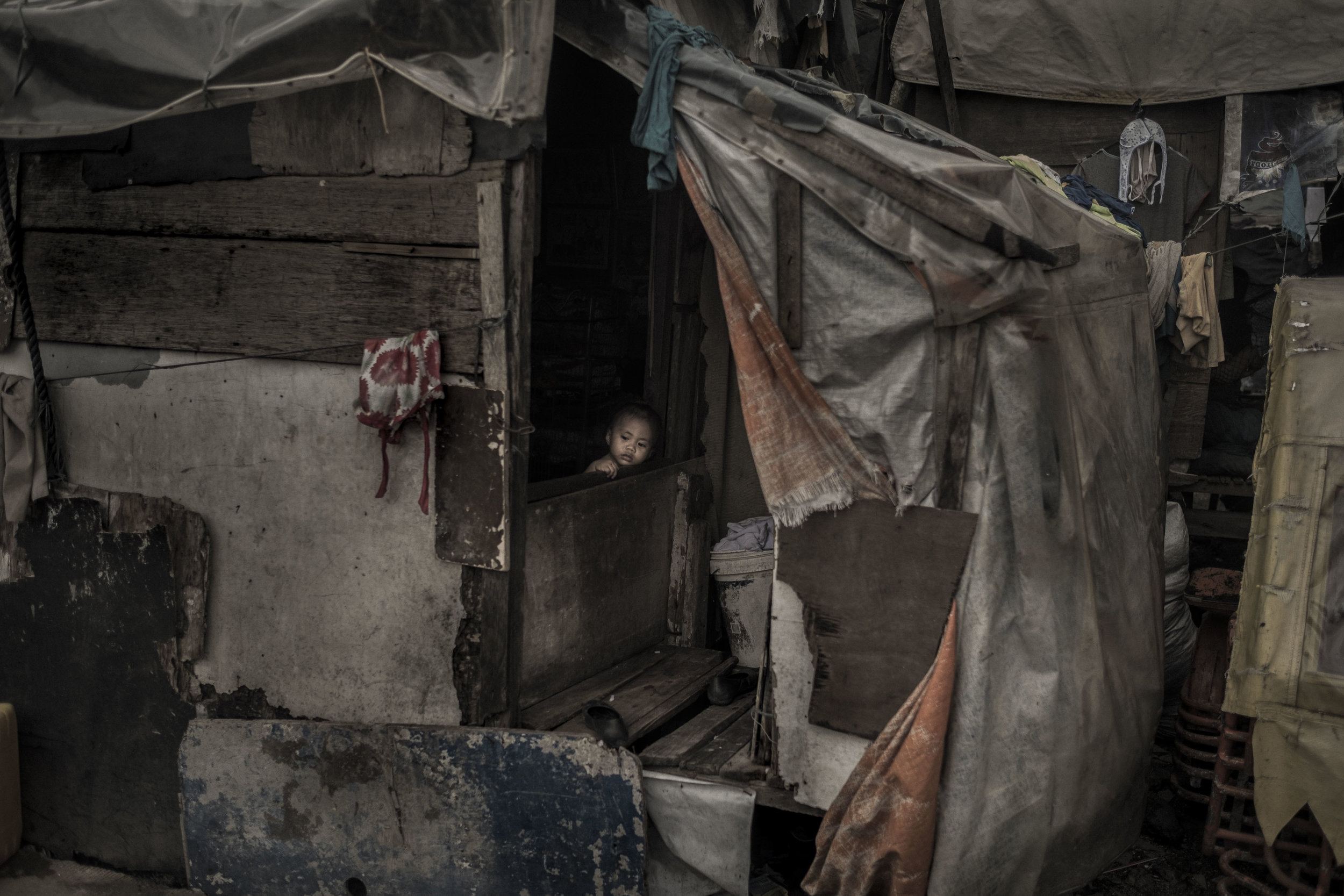  A child looks outside from a house made of materials found in the Pasig River. 