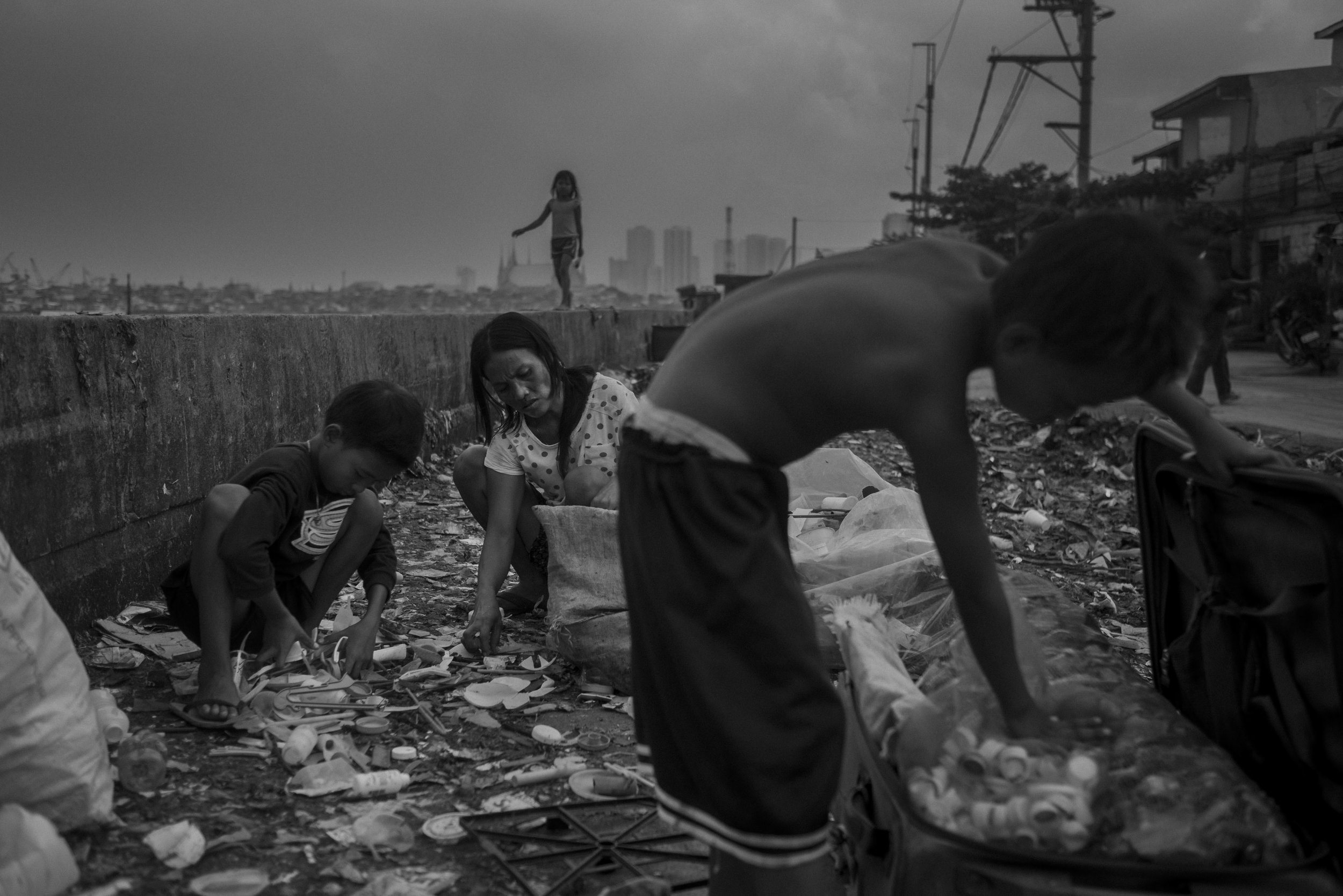  Jocelyn Balbin and her sons Mark and Reynaldo collect water caps and other recyclable materials, next to Pasig River, in Manila, Philippines. 