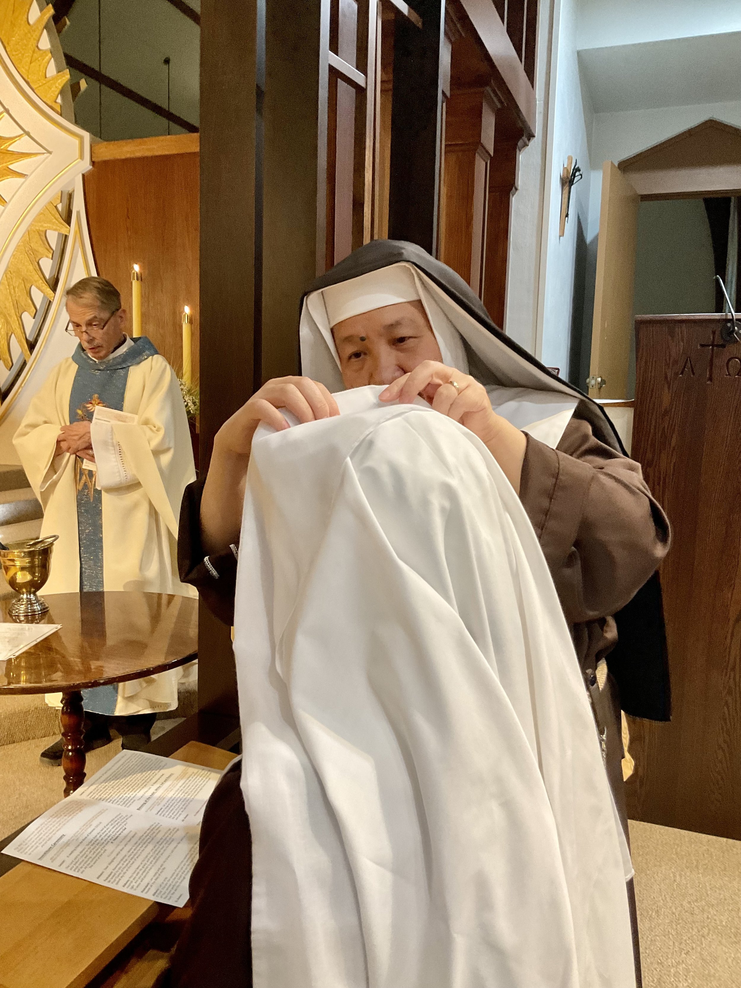 The final touch of receiving the Holy Habit—the white veil of a Novice.