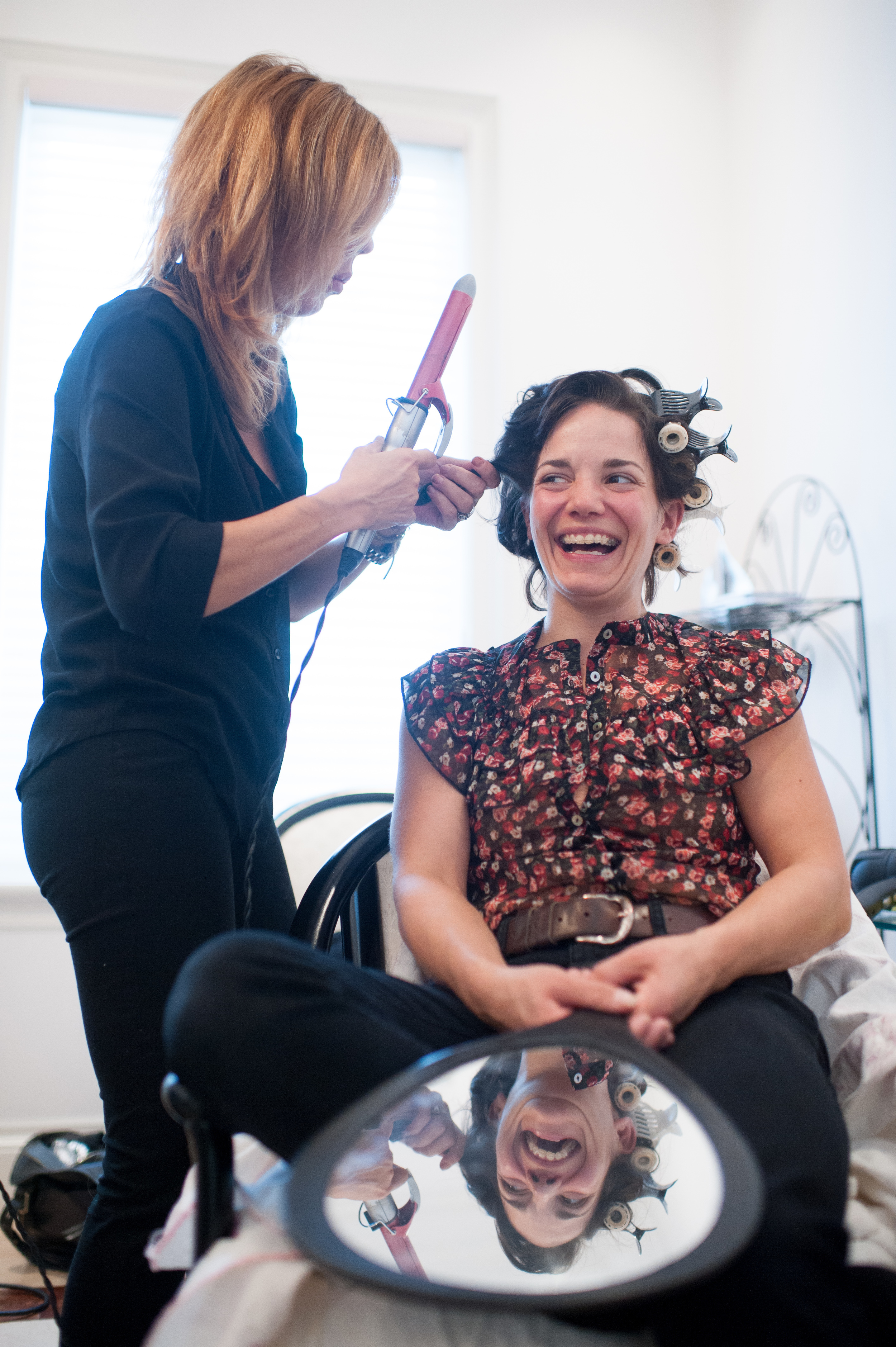  bridesmaid laughs while having her hair done at brides home. 