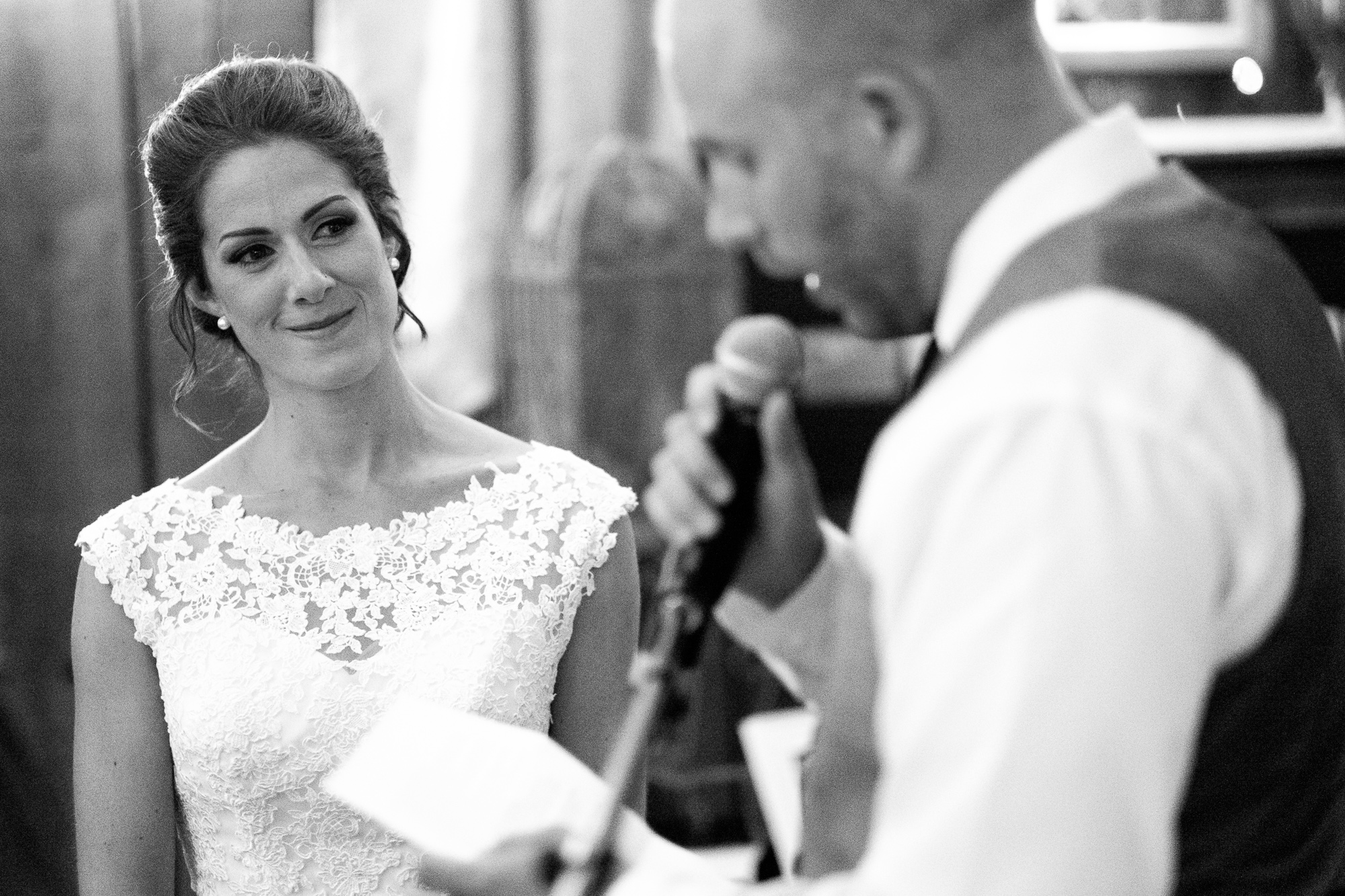 Rebecca looks on as Jeff gives a toast to the bride during his speech at their wedding reception.