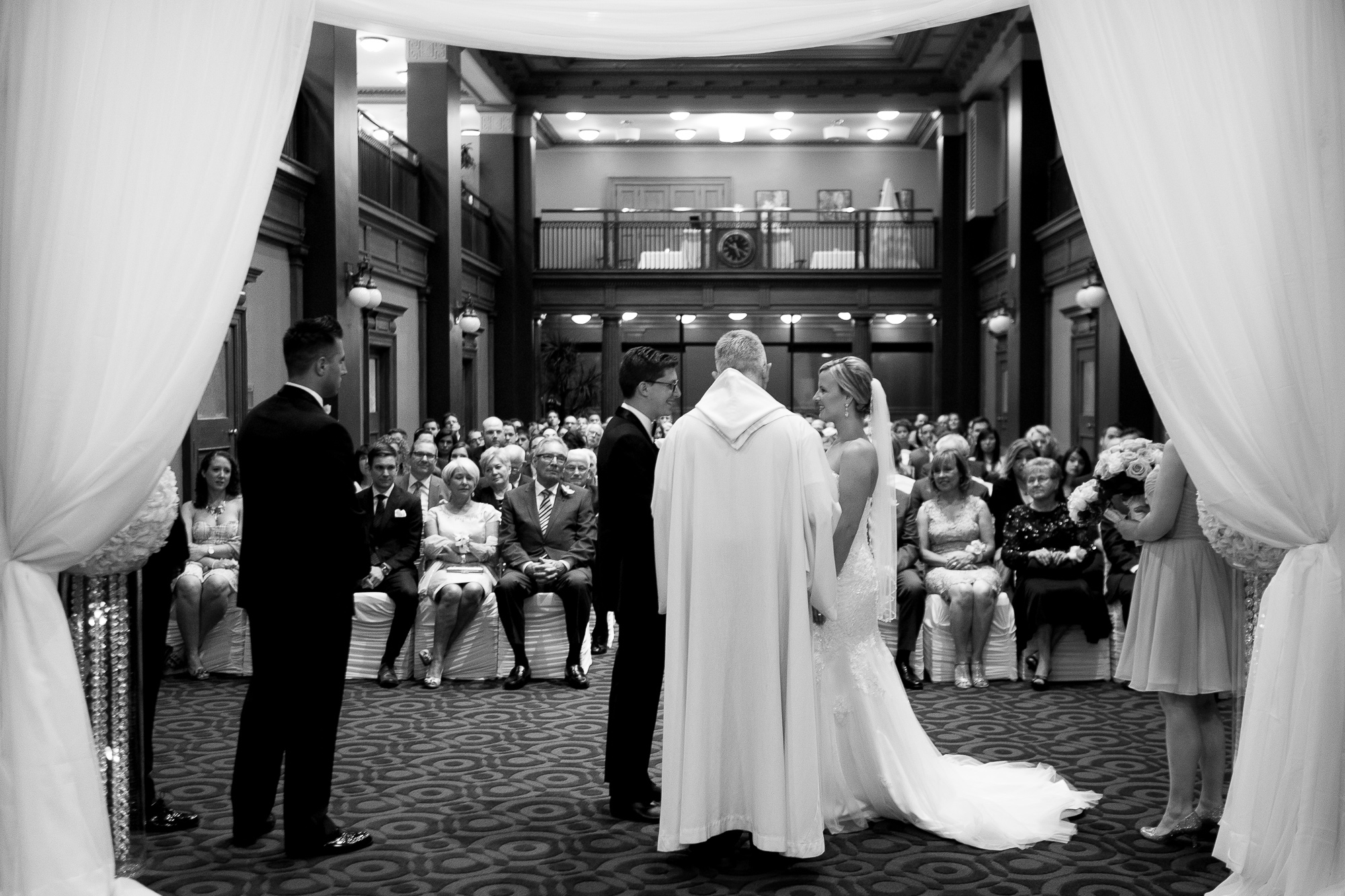  Danielle + Eric exchange their wedding vows as the guests look on during their ceremony at One King West Hotel In Toronto. 