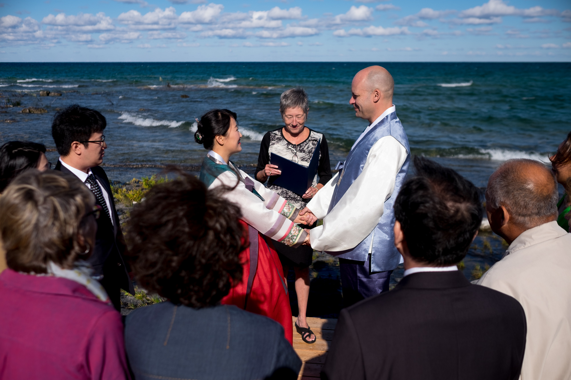  Guests look on as Joohee + Joel are married on the shore of Georgian Bay in Tobermory. 