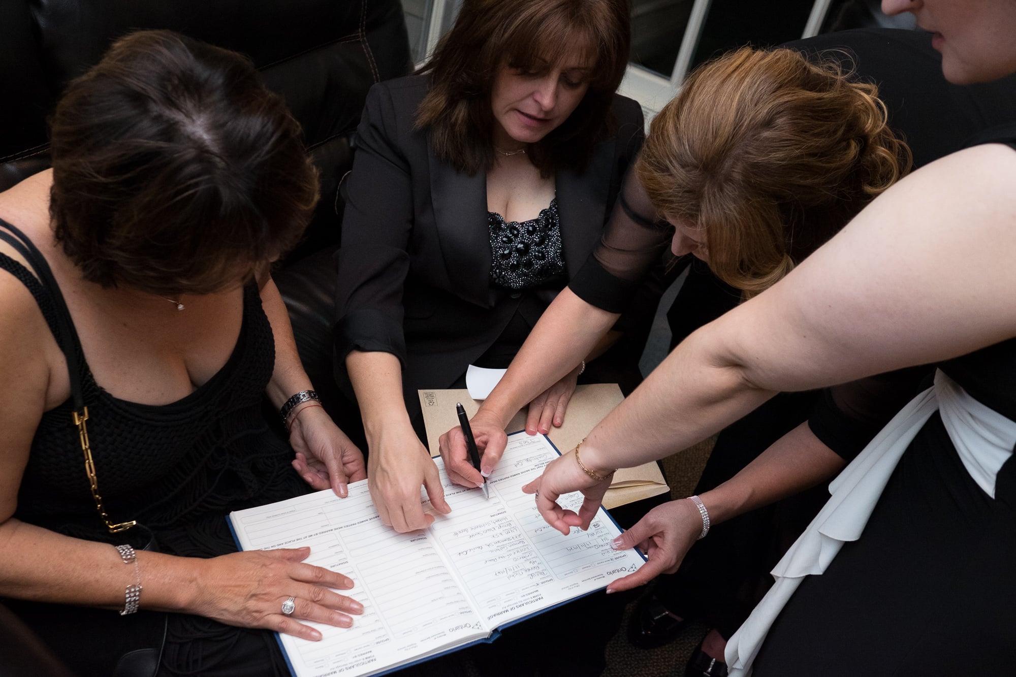  Everyone helps during the signing of the marriage license during Renee + Senem's wedding at Langdon Hall. 