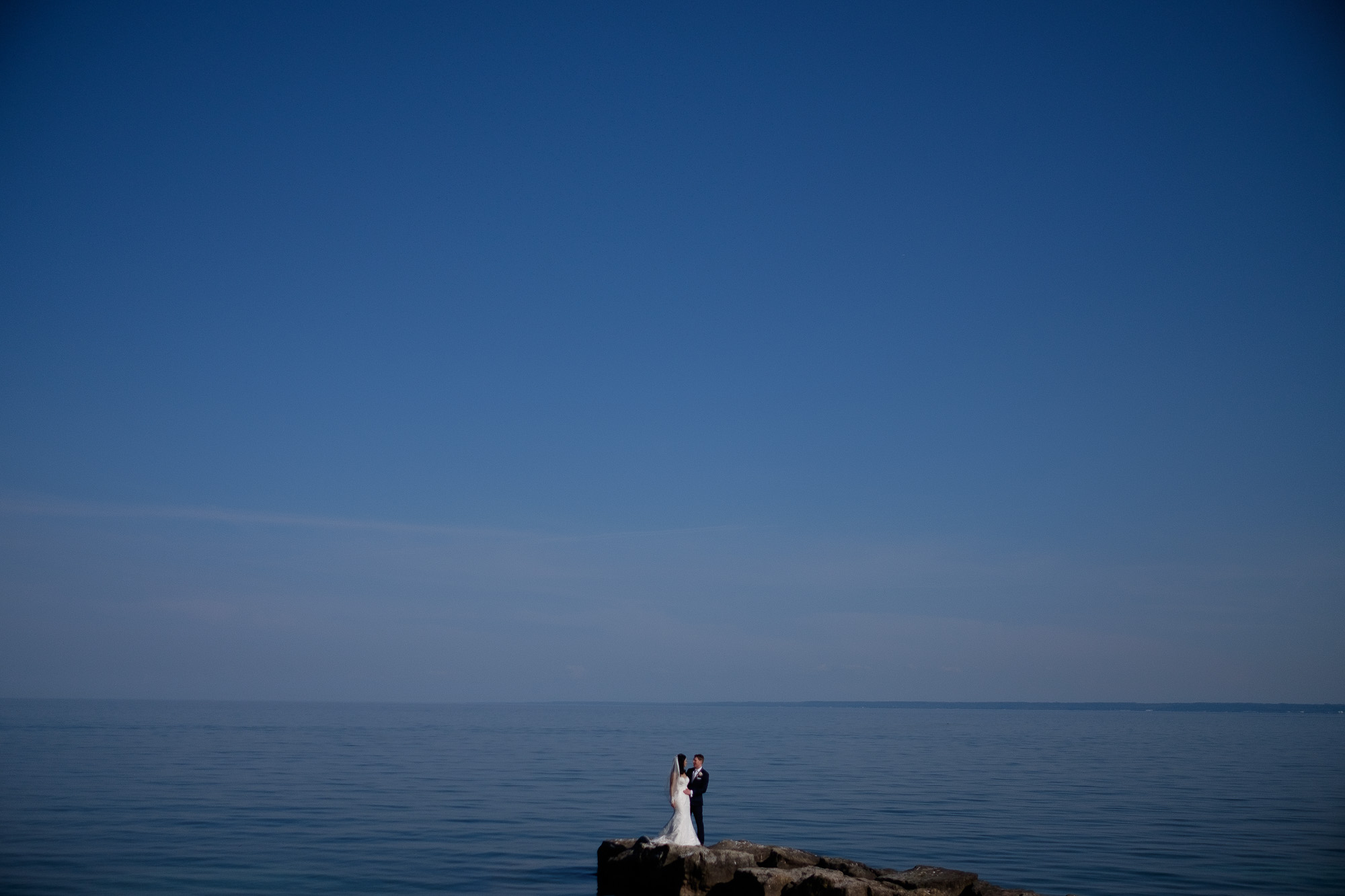  Laura + Chris pose for a dramatic wedding portrait on the shores of Lake Ontario at the Paletta Mansion in Mississauga. 