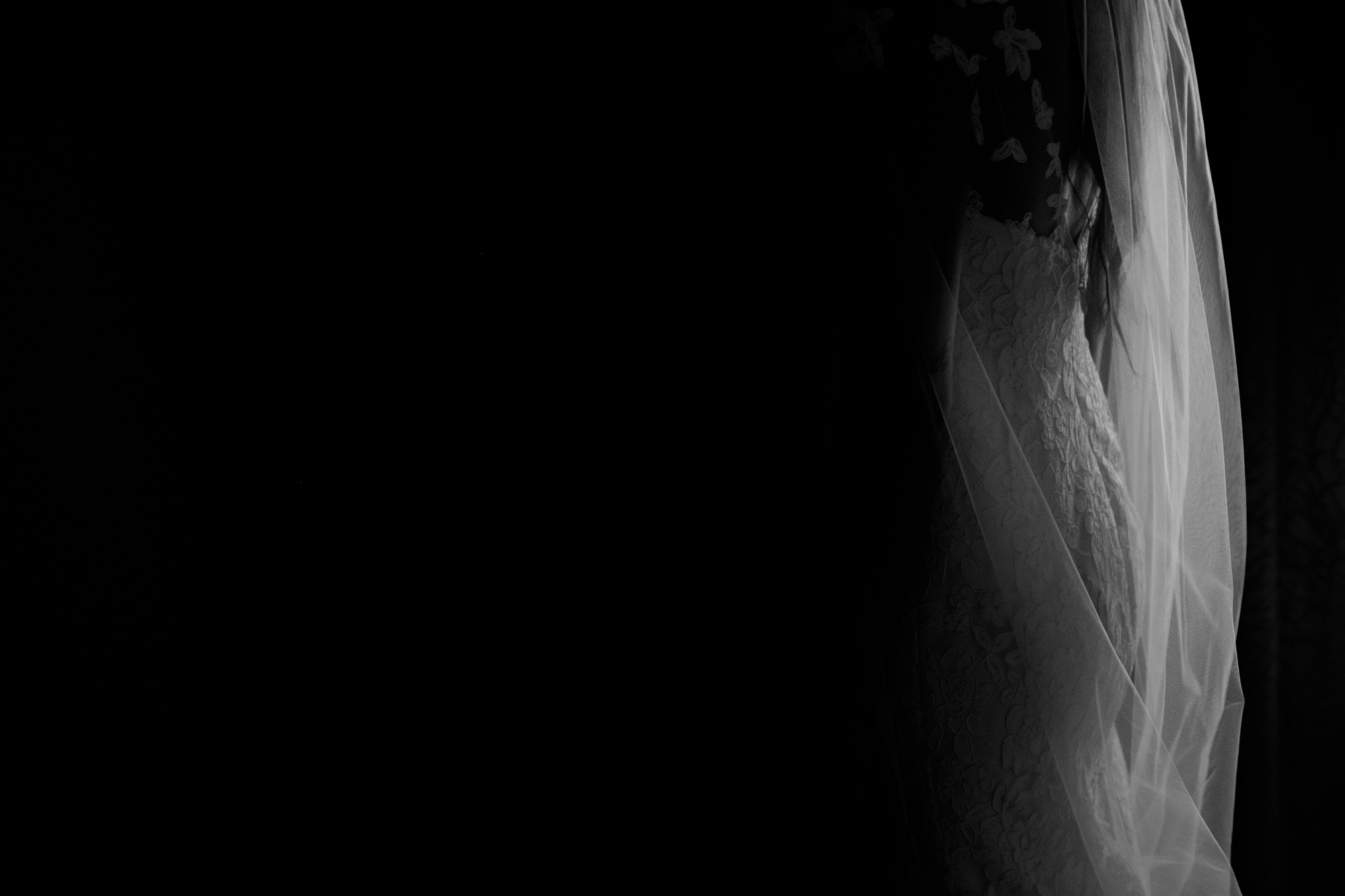  A black and white detail photograph of a bride's wedding dress. 