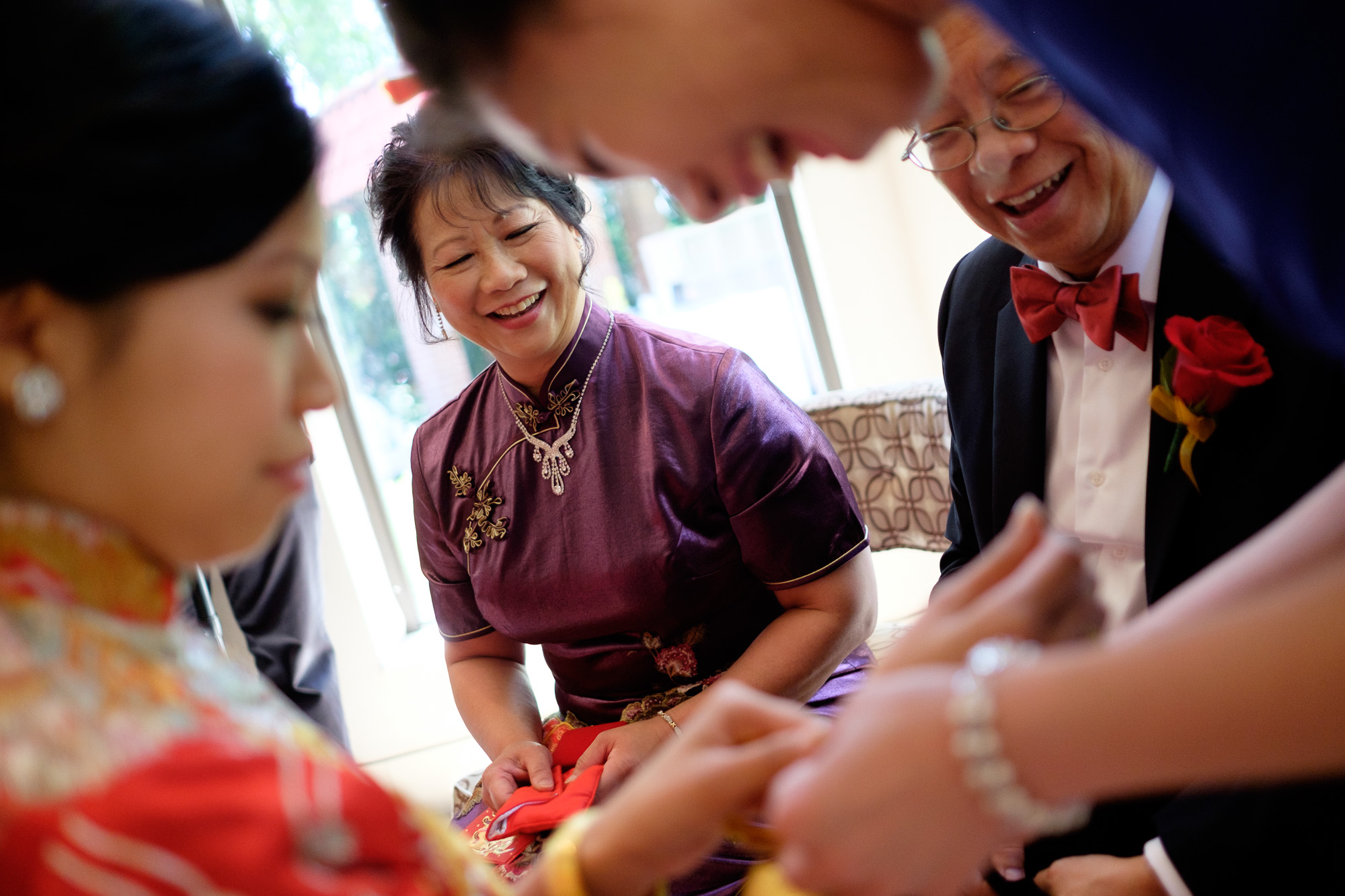  Jonathan's parents look on as Sherry tries on the jewelry they gave her during the traditional Chinese Tea ceremony.&nbsp; 