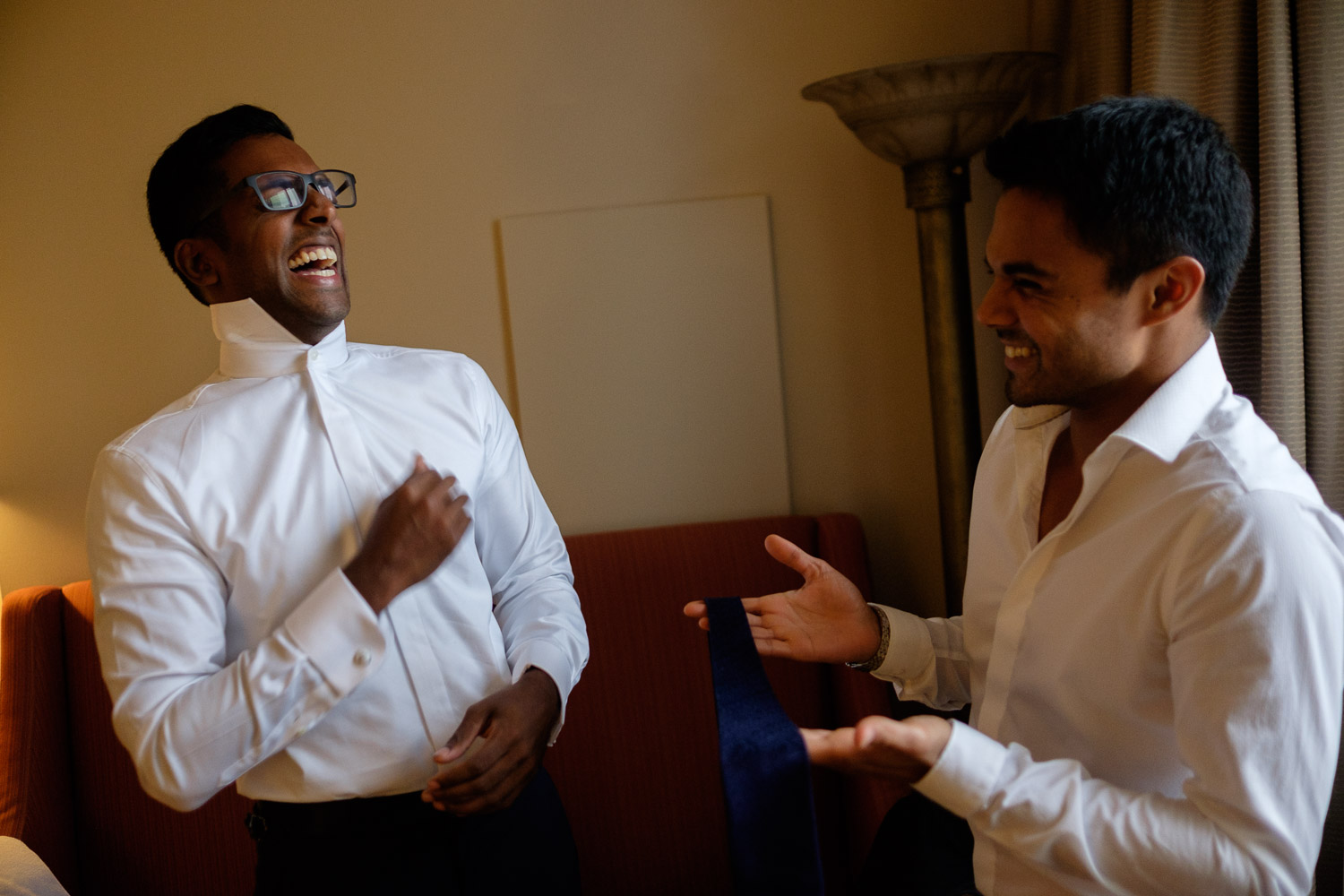  Trevin shares a laugh with one of his groomsmen as they get dressed in their suite at the Hyatt Yorkville in Toronto before the wedding at the Art Gallery of Ontario.&nbsp; 