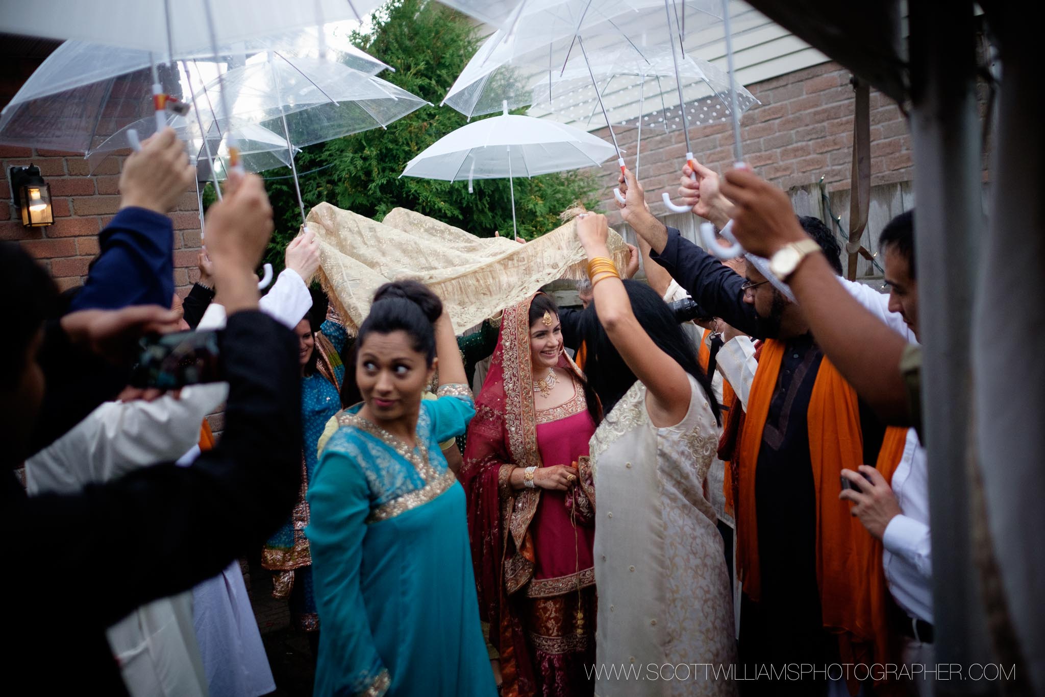 The bride makes her entrance to their backyard wedding ceremony on a rainy day.