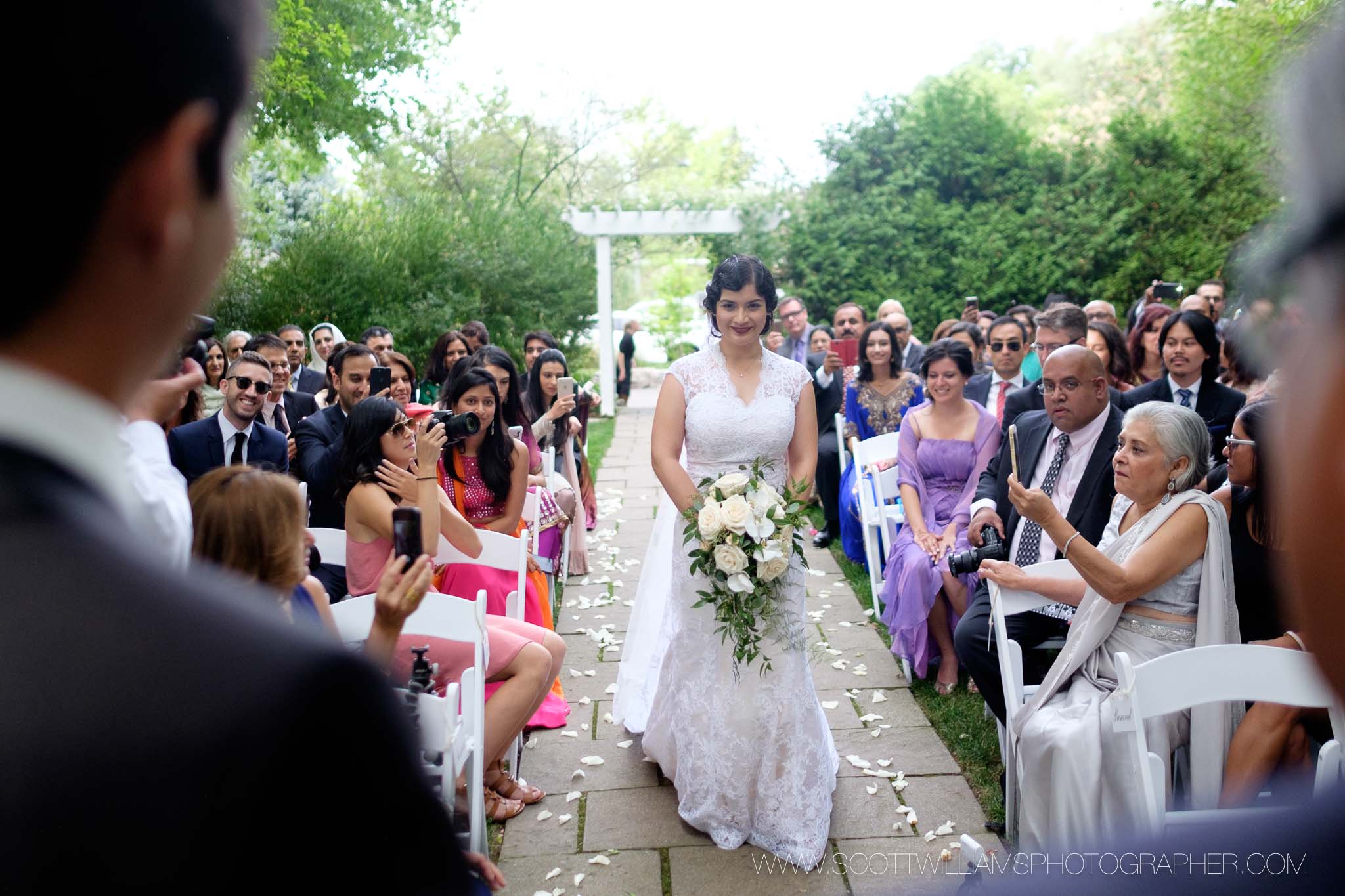  The bride walks down the aisle during her outdoor wedding ceremony at the Ancaster Mill in Ancaster, Ontario. 