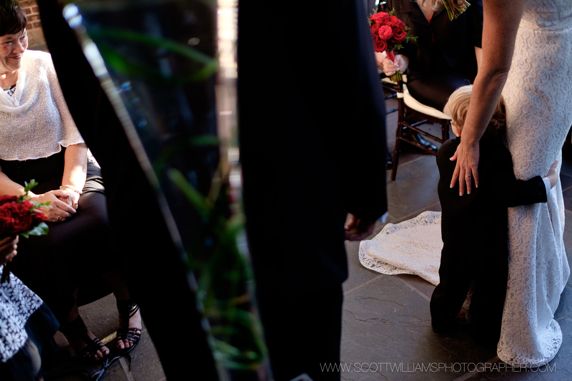  A photograph of the ring bearer holding onto the bride during the wedding ceremony during a smaller, intimate wedding at Langdon Hall in Cambridge, Ontario. 
