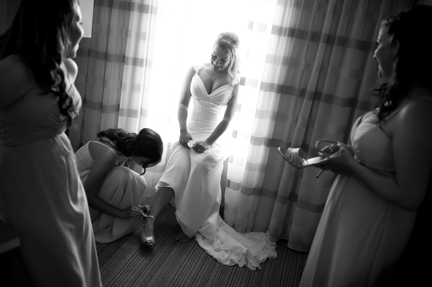 Michelle's bridesmaids help her get ready in their hotel room before her outdoor wedding ceremony at the WhistleBear Golf & Country Club in Cambridge, Ontario. I love the framing in this image created by the strong highlight of the window behind Michelle, it immediately draws the viewers eye directly to the subject, in this case the bride! The lighting and expressions of the two bridesmaids, who are also looking at Michelle, add to the photograph.