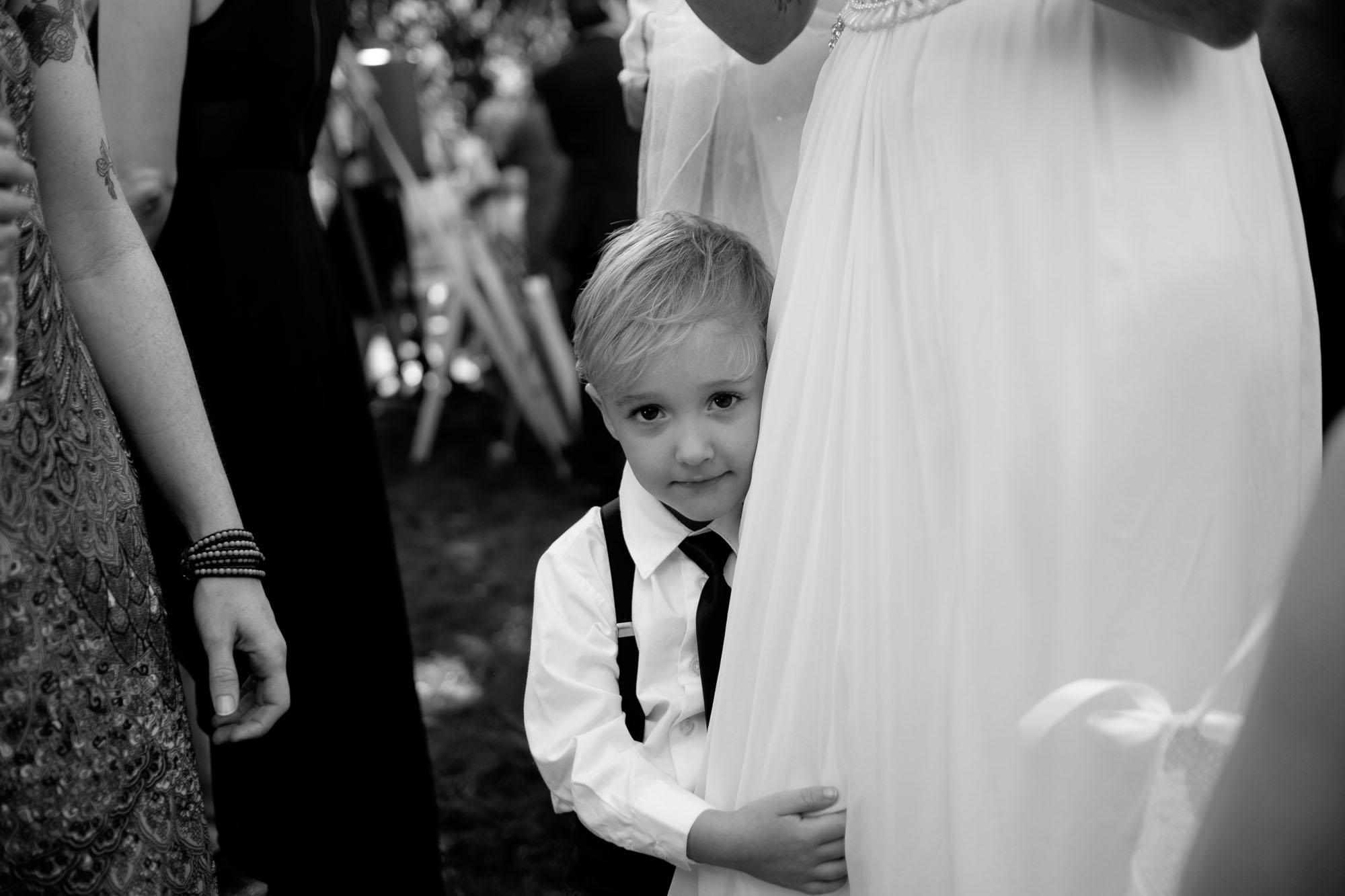  The brides son clings to her wedding dress during cocktail hour at their backyard wedding in Barrie, Ontario. &nbsp;Photograph by Scott Williams. 