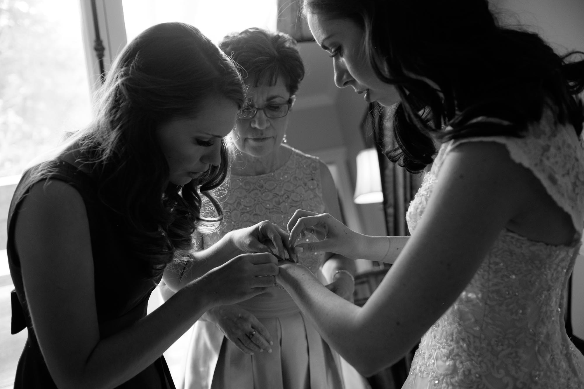 Amanda is helped with her bridal jewelry by her mother and sister in the suite at Langdon Hall.