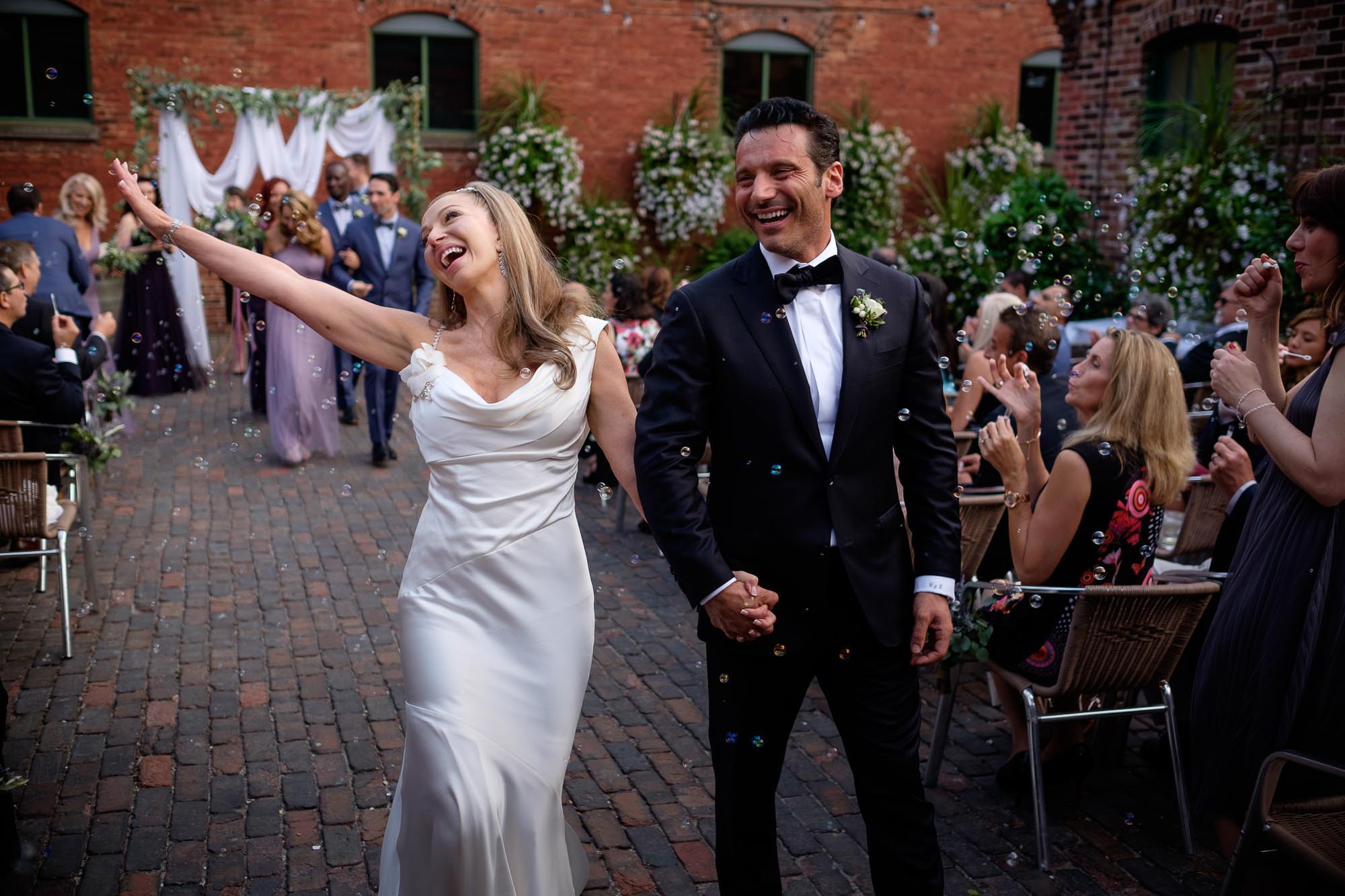 the bride and groom dance their way down the aisle after their wedding ceremony at Archeo in Toronto's Distillery District.