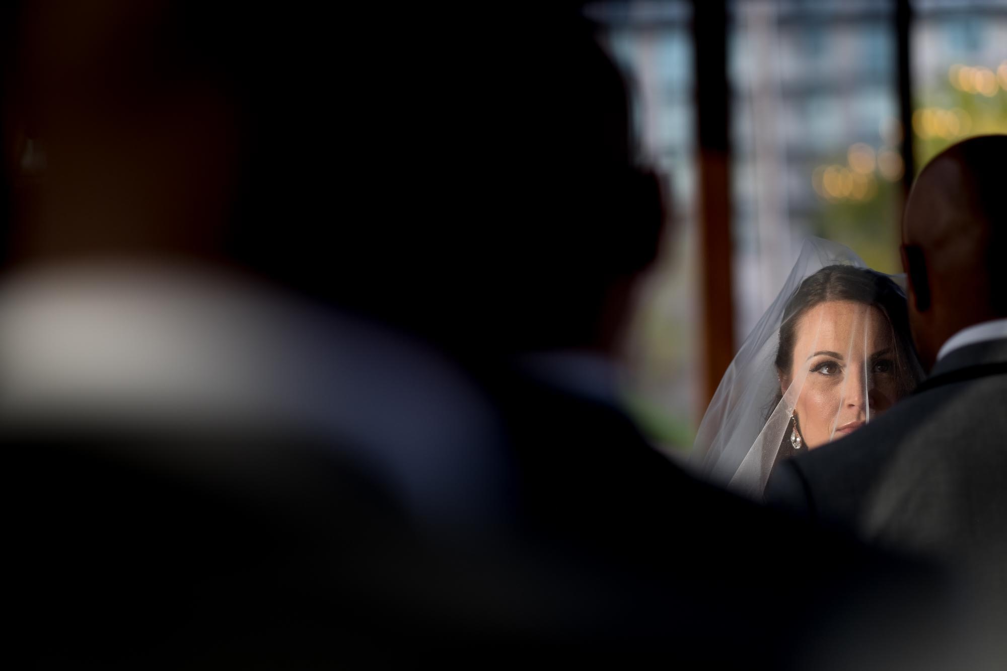  The bride looks on as the groom reads his vow during their wedding ceremony at the Cambridge Mill. 