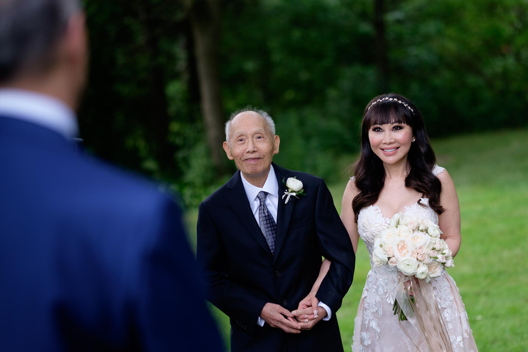  the bride is escorted down the aisle by her father during their outdoor wedding ceremony at Langdon Hall in Cambridge, Ontario. 