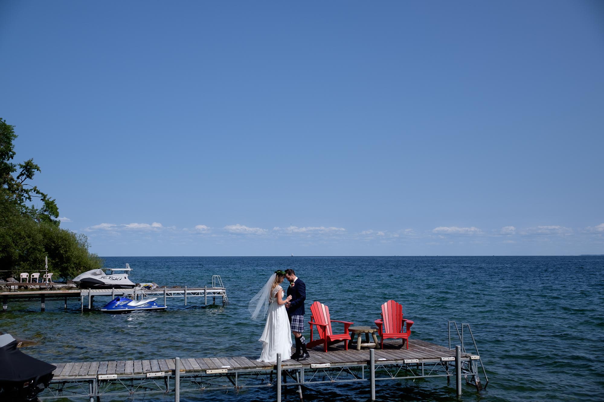 the bride and groom enjoy their first look on a dock on Lake Simcoe before their backyard wedding.