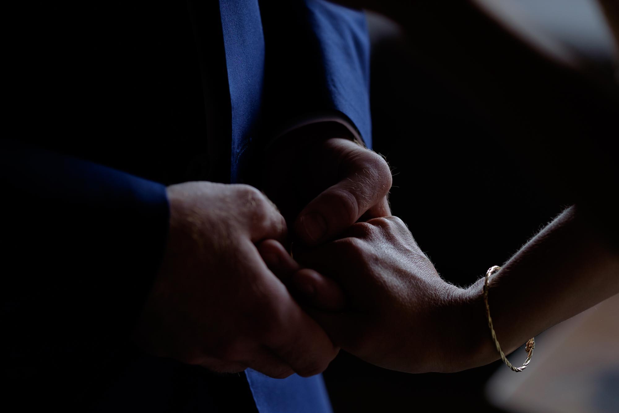  the bride and grooms hands embrace during the wedding ceremony. 