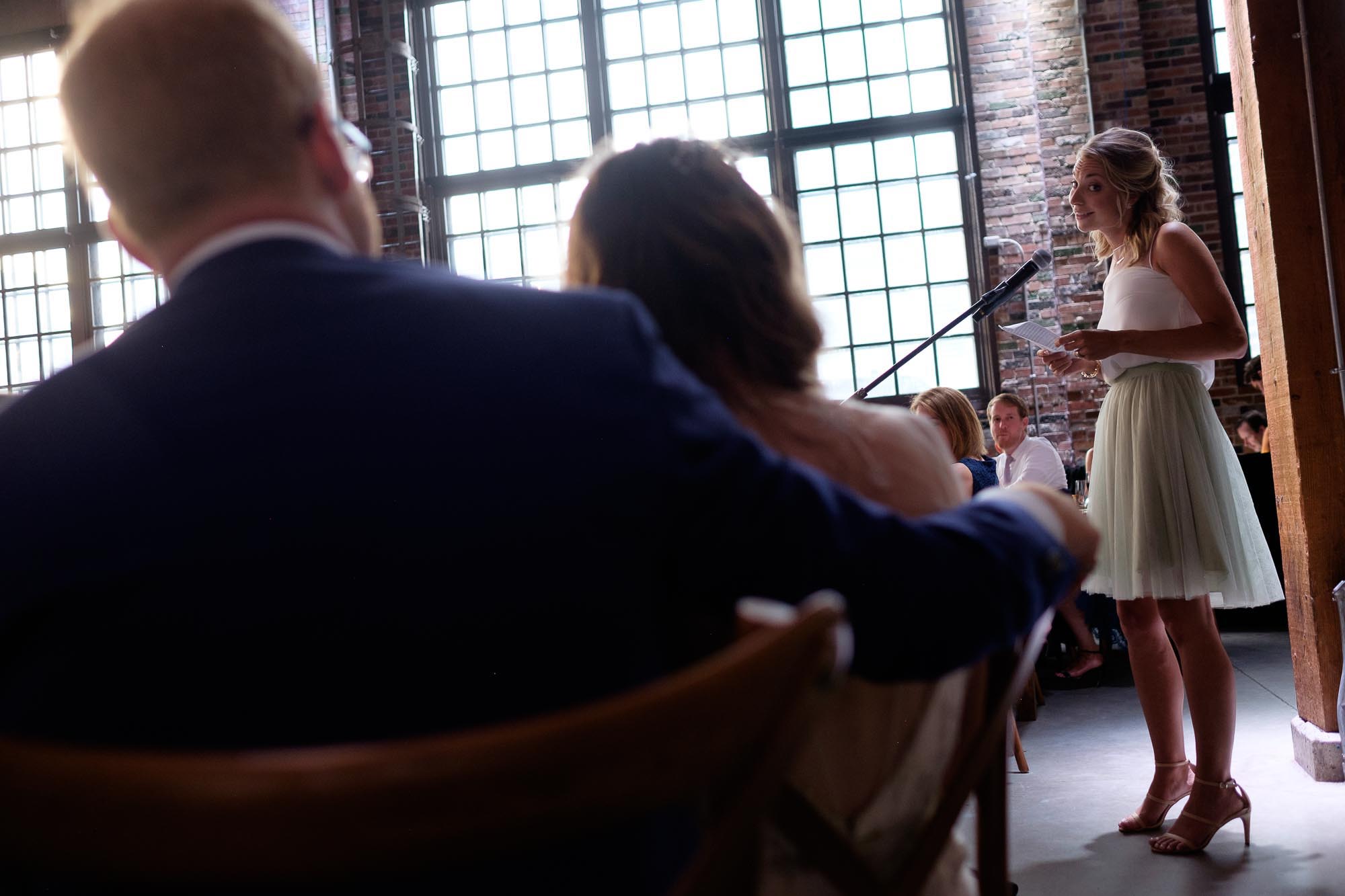  the bride and groom listen to a speech during &nbsp;a wedding reception at SteamWhistle Brewery in Toronto. 