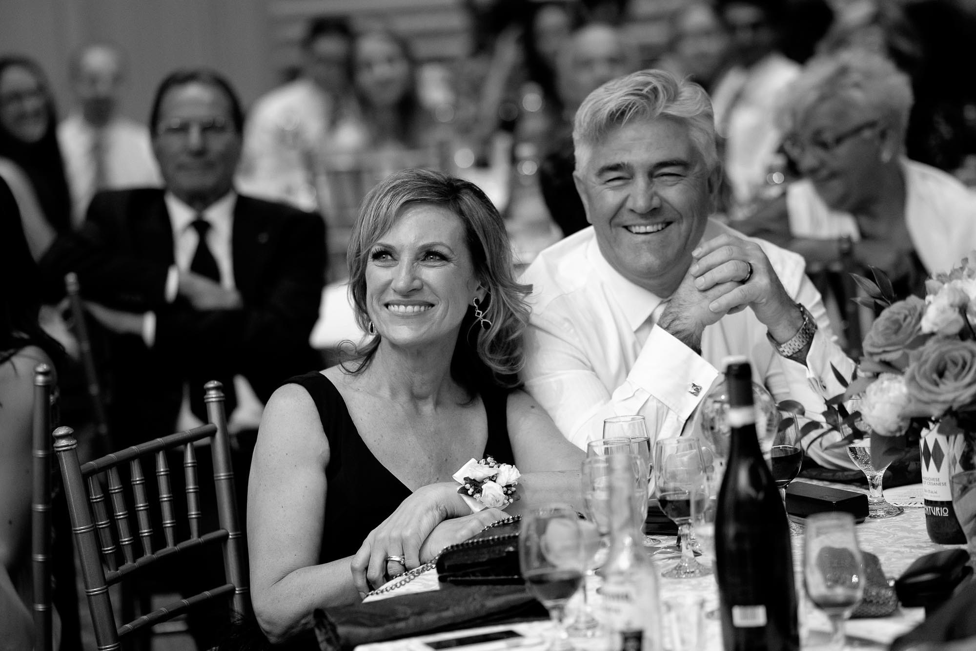  The bride's parents listen and react to the brides speech during their wedding reception. 