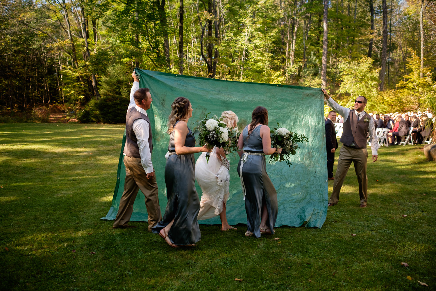  A bride sneaks past her wedding guests before her backyard outdoor wedding ceremony at their private residence in Muskoka, Ontario by Toronto wedding photographer Scott Williams. 