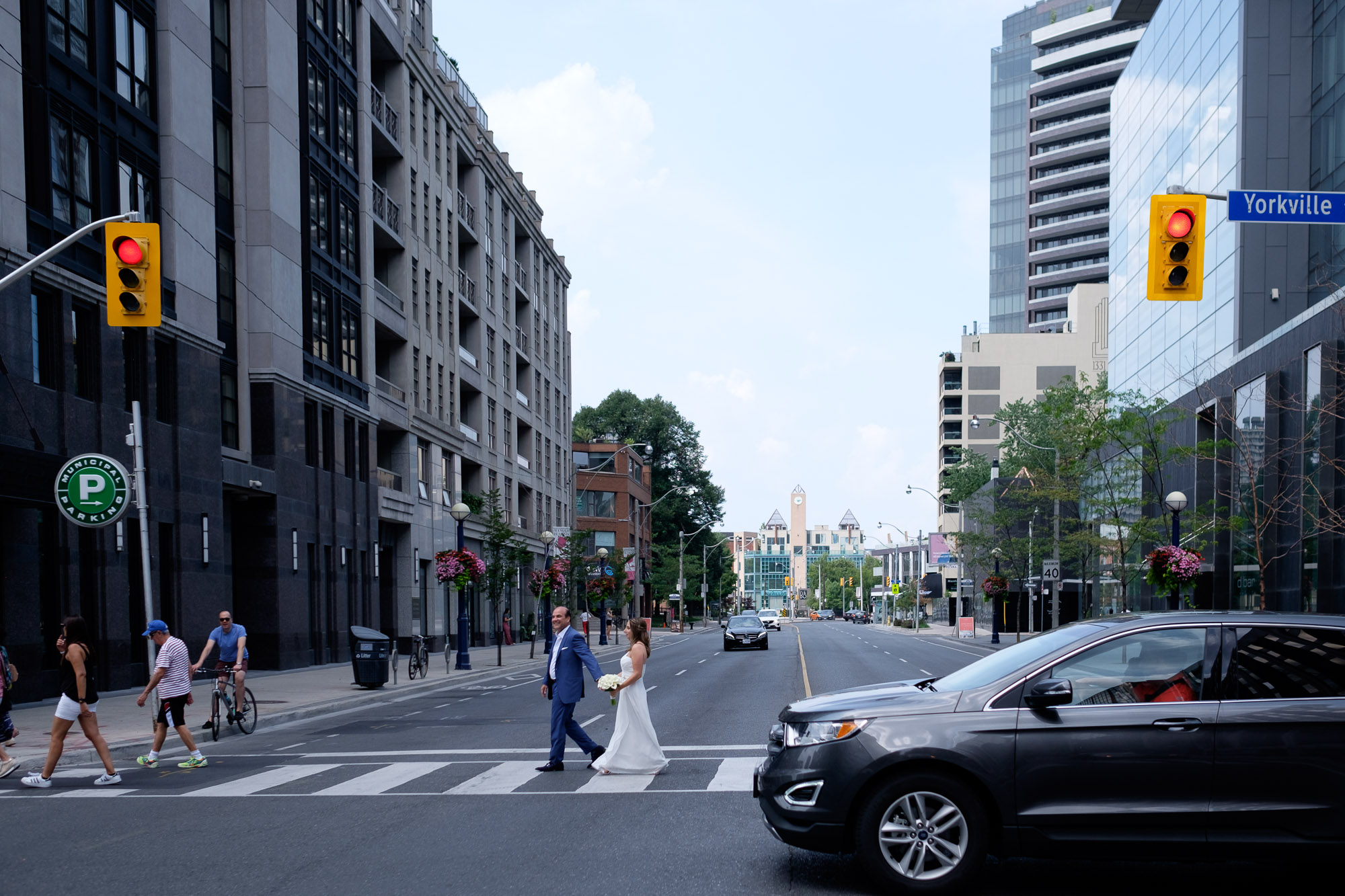  Bride and groom cross a busy Toronto intersection while having wedding portraits taken in Toronto’s Yorkville neighbourhood. 