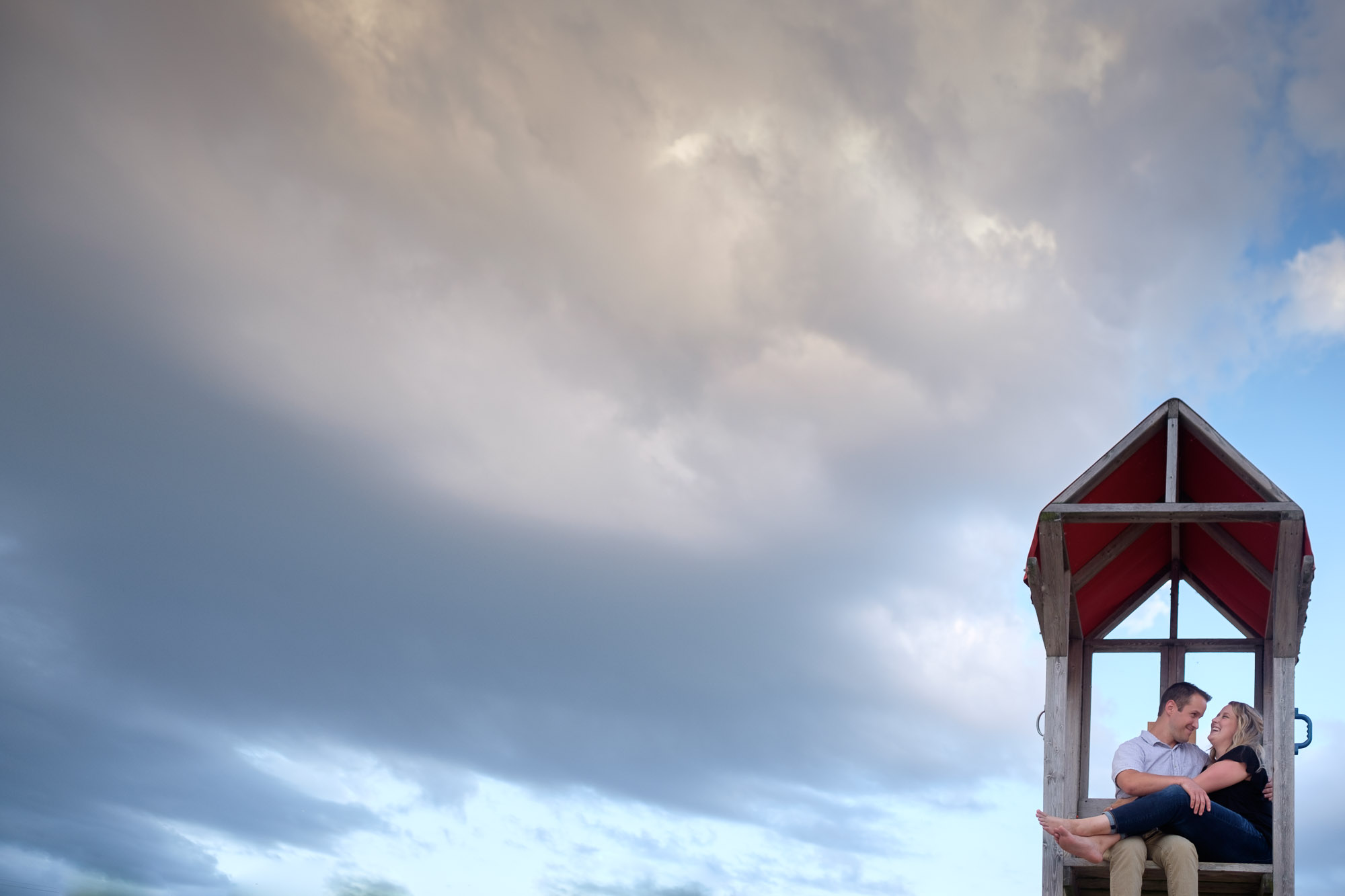  Alex and Colton cuddle in a lifeguard station during their beach engagement shoot in Goderich Ontario. 