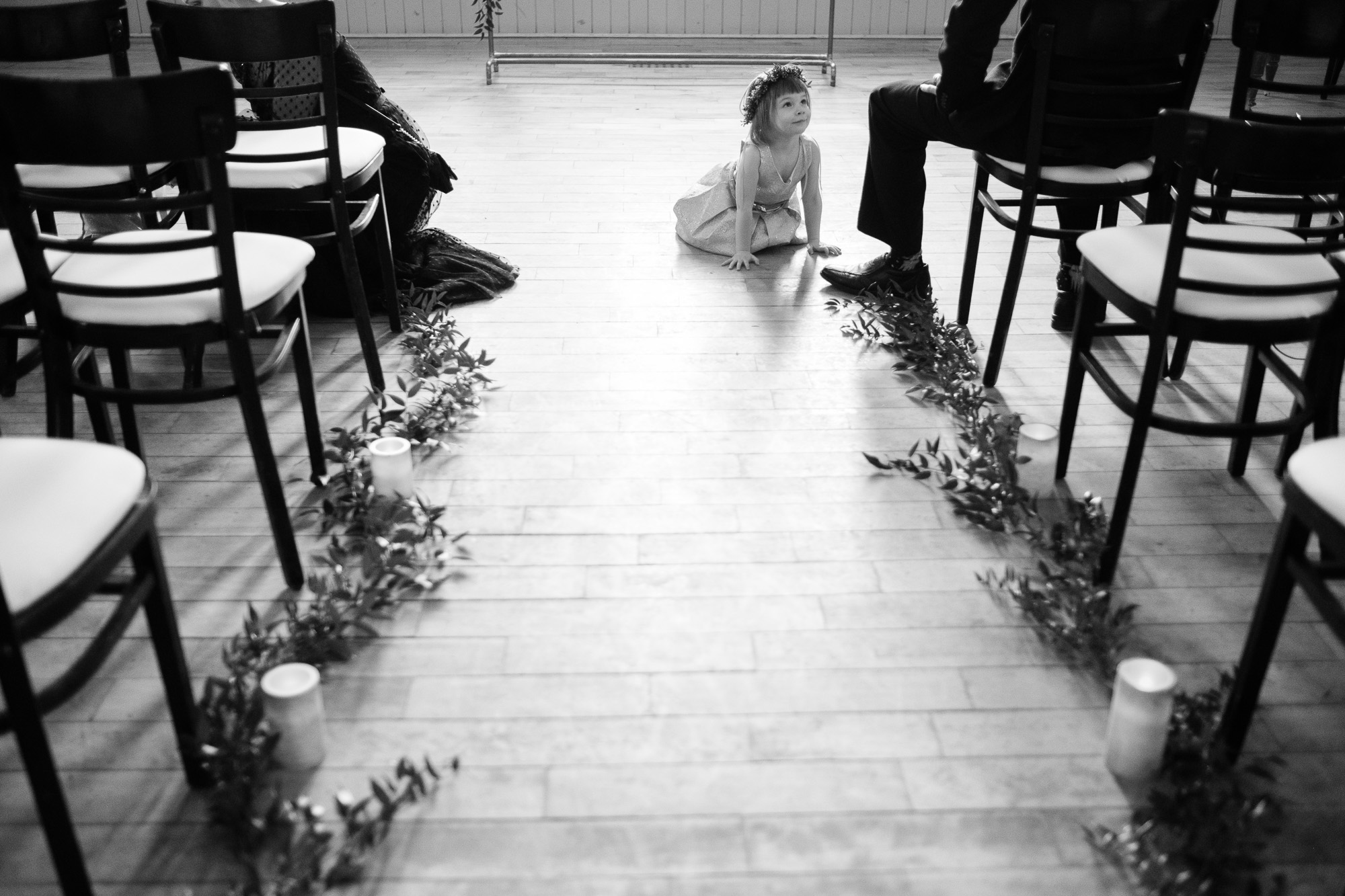 The flower girl hangs out in wedding aisle before the winter wedding ceremony at the Enoch Turner Schoolhouse in Toronto.