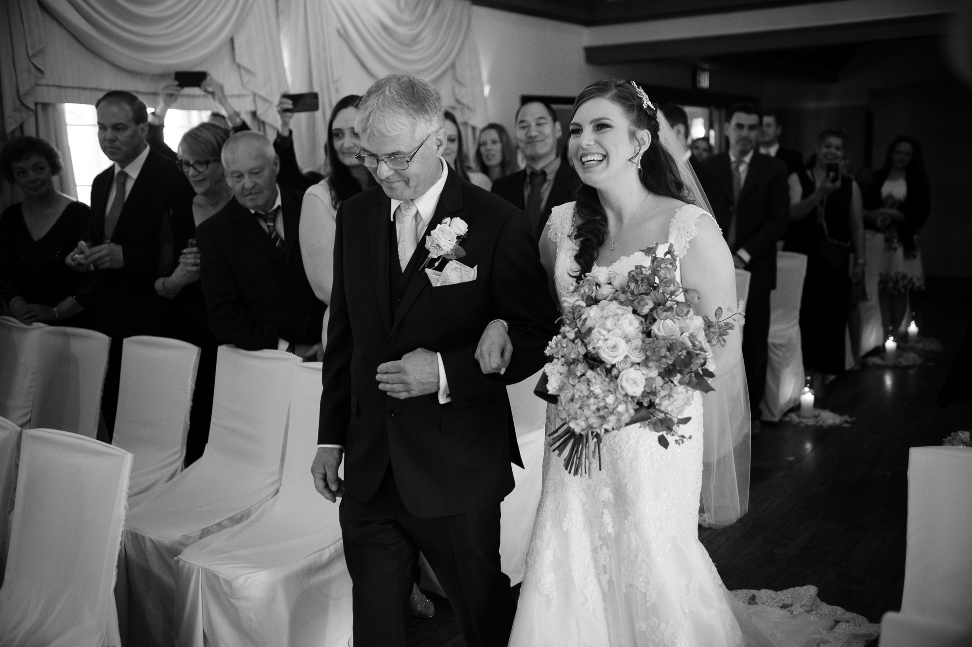  The bride is escorted down the aisle by her father in the this black and white wedding photograph from a wedding ceremony at the Glenerin Inn just outside of Toronto. 