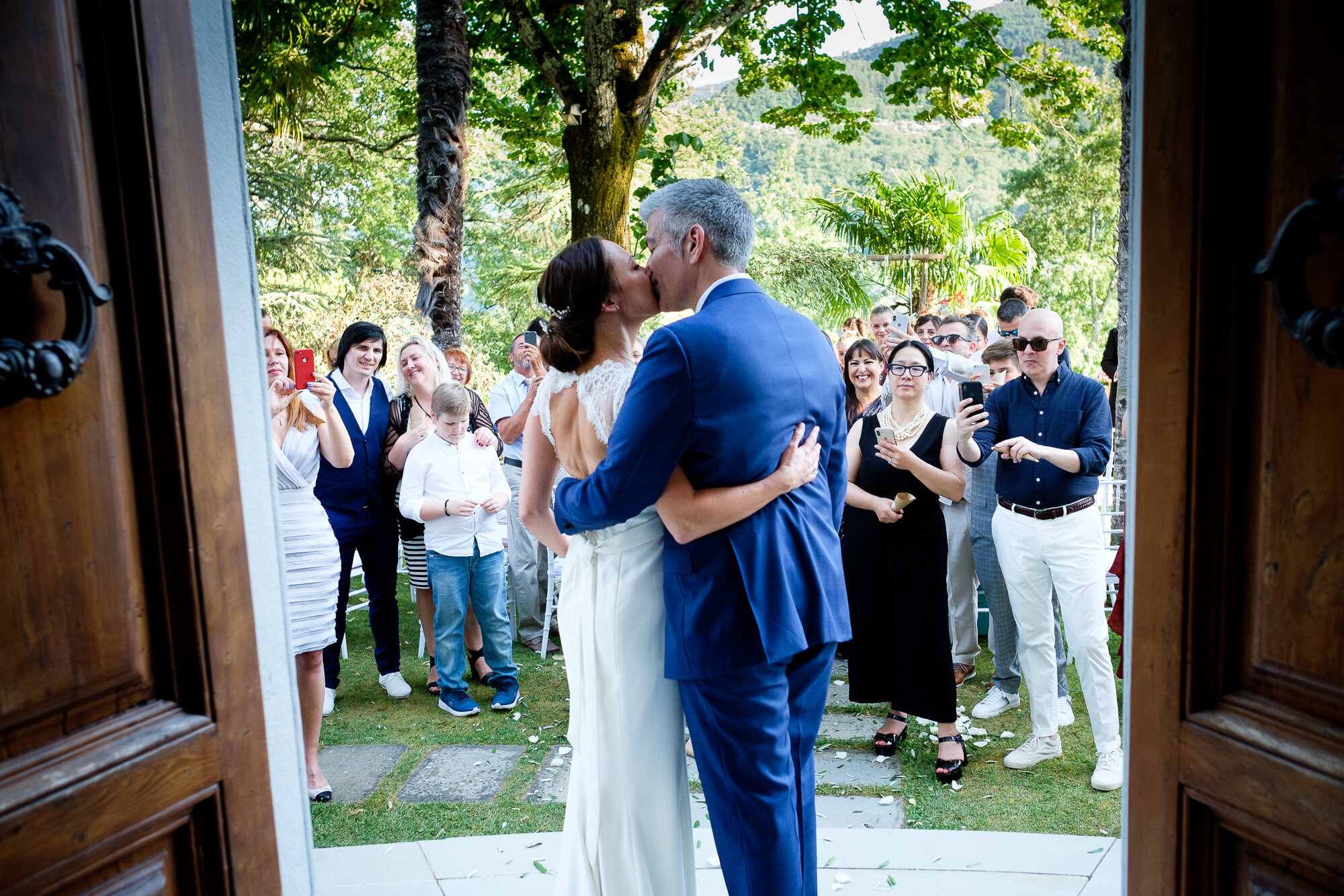  Elena + Steve share a kiss while their wedding guests look on after their wedding ceremony in the hills of Tuscany, Italy by wedding photographer Scott Williams (www.scottwilliamsphotographer.com) 