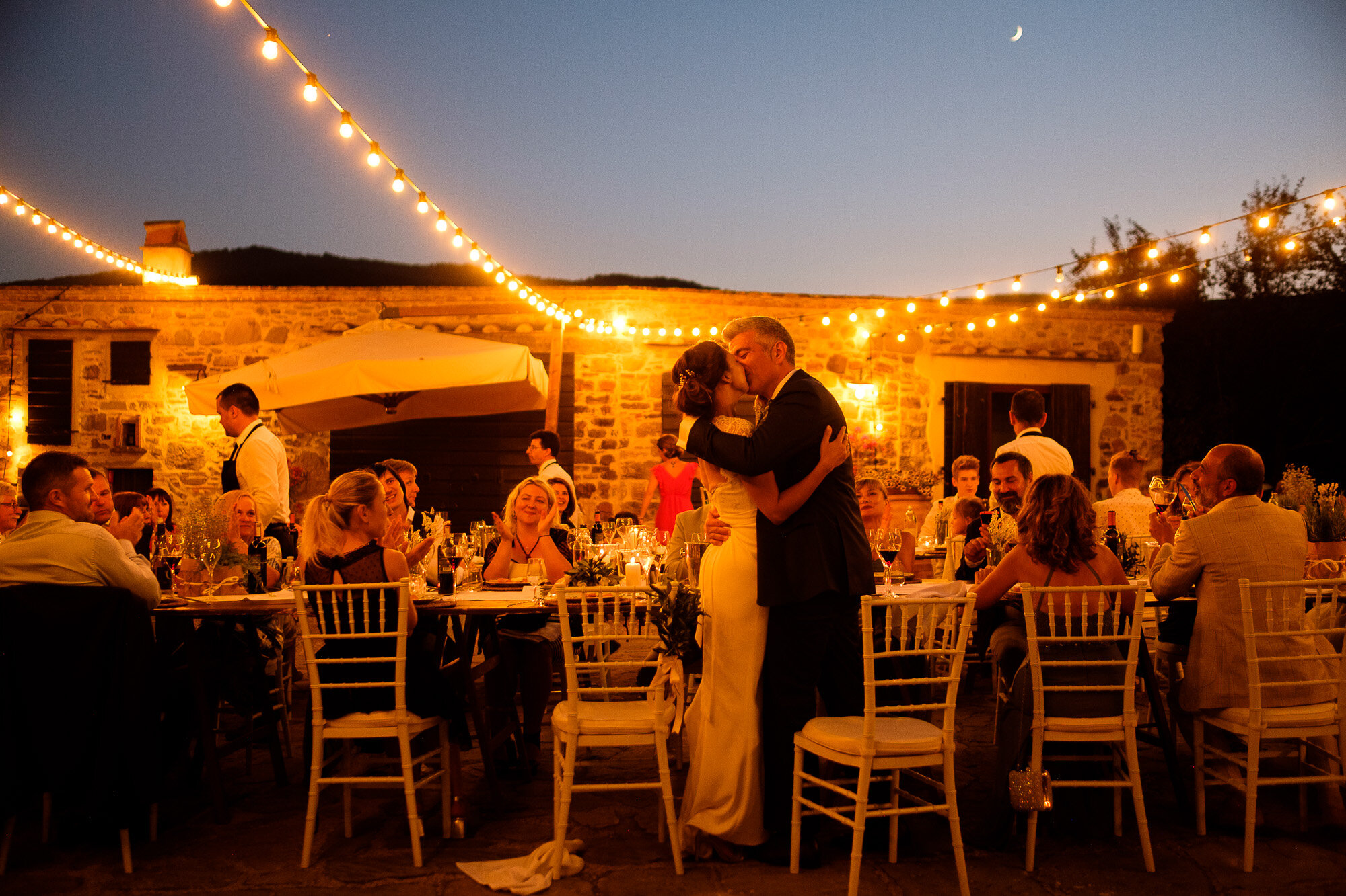  Elena + Steve share a kiss under the lights during their outdoor wedding reception at a villa in Tuscany, Italy during their destination wedding by wedding photographer Scott Wiliams (www.scottwilliamsphotographer.com) 