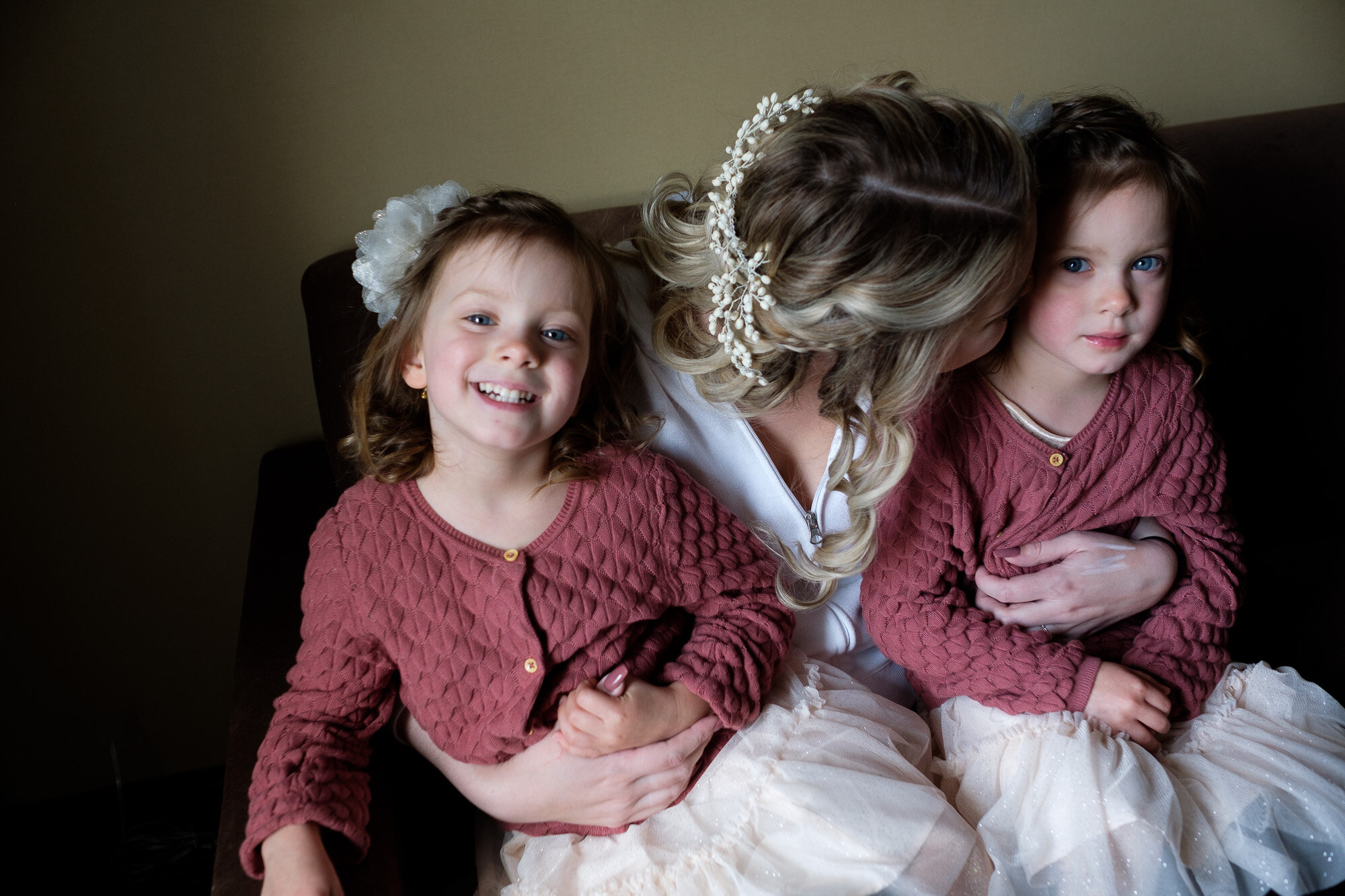  The bride snuggles with her two flower girls while getting ready in her suite at a St. Jacobs hotel before her wedding at the Three Bridges event centre located outside of Waterloo, Ontario.  Photograph by Toronto wedding photographer Scott Williams