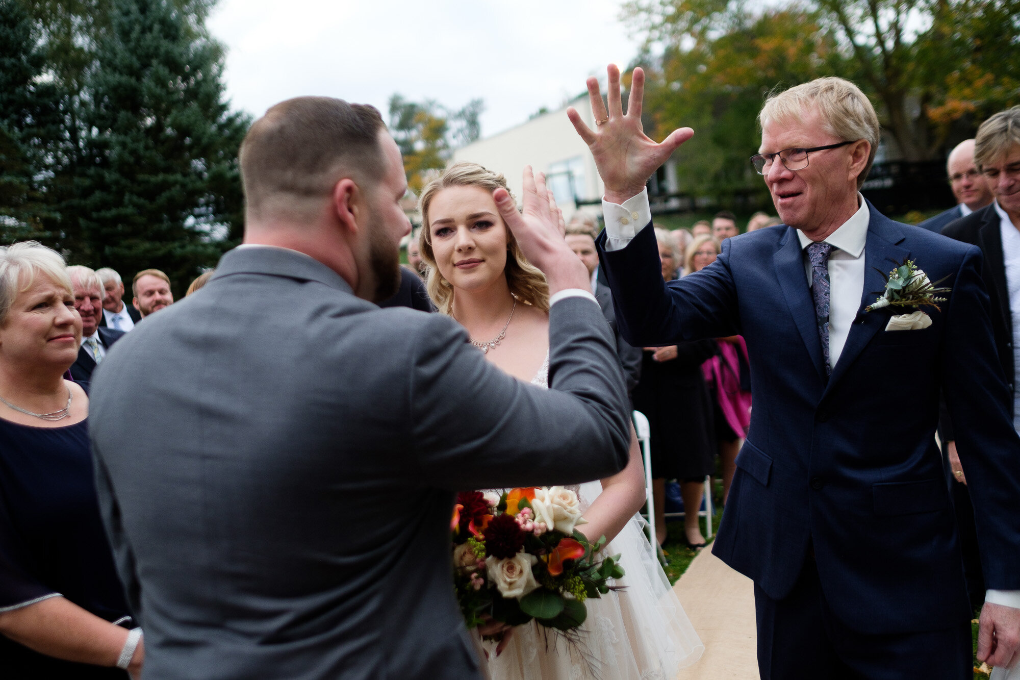  The groom fist bumps the father of the bride during the wedding ceremony at the Three Bridges event centre located outside of Waterloo, Ontario. Photograph by Toronto wedding photographer Scott Williams. 