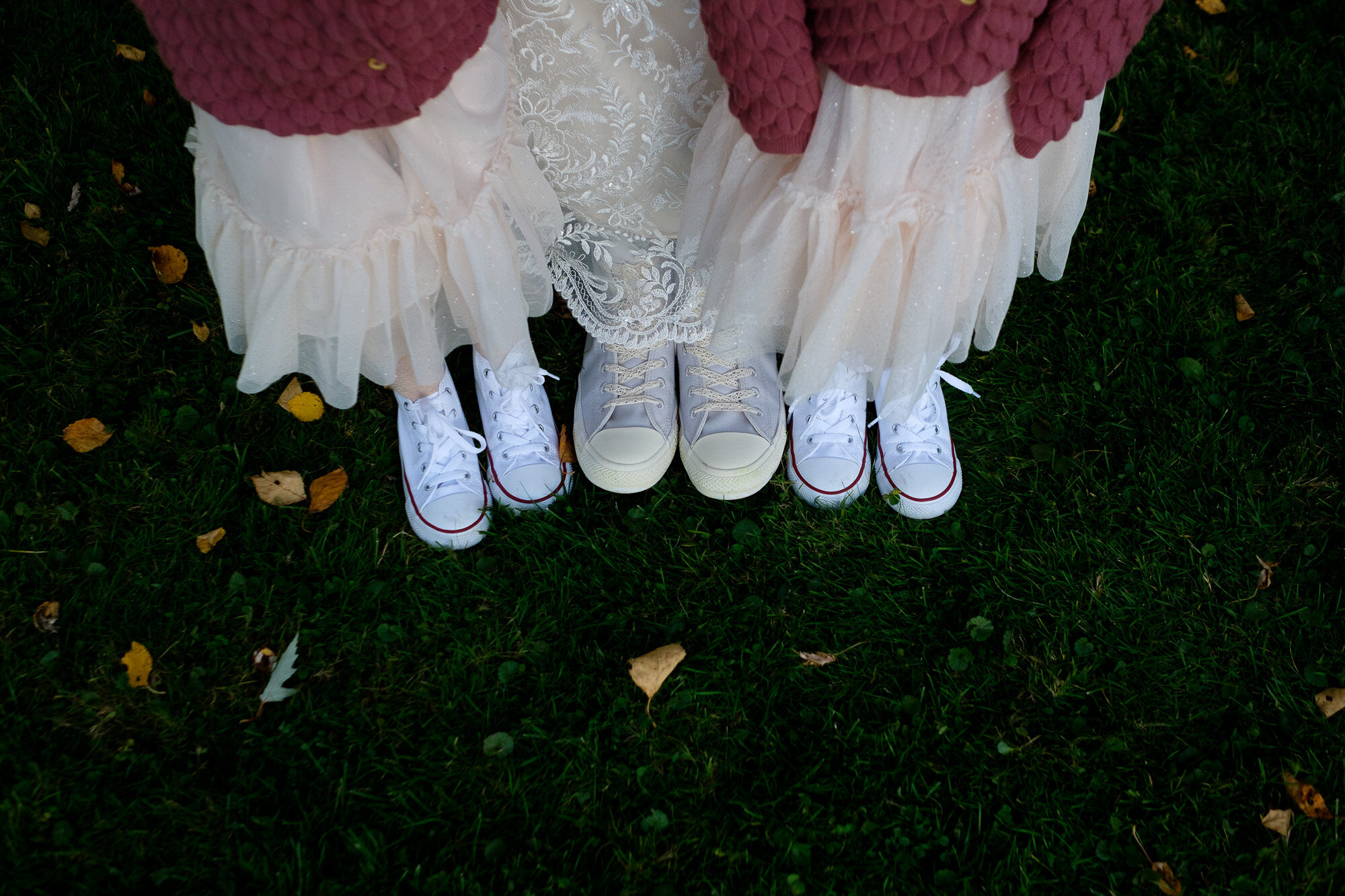  A wedding detail photograph of the bride and her flower girls with matching running shoes  at the Three Bridges event centre located outside of Waterloo, Ontario. Photograph by Toronto wedding photographer Scott Williams. 