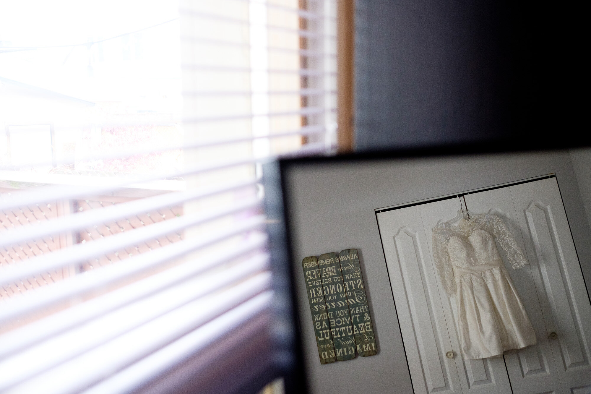  A wedding detail photograph of Emily’s wedding dress hanging in her bedroom before their wedding at Archeo in Toronto’s Distillery district by Toronto Wedding Photographer Scott Williams. 